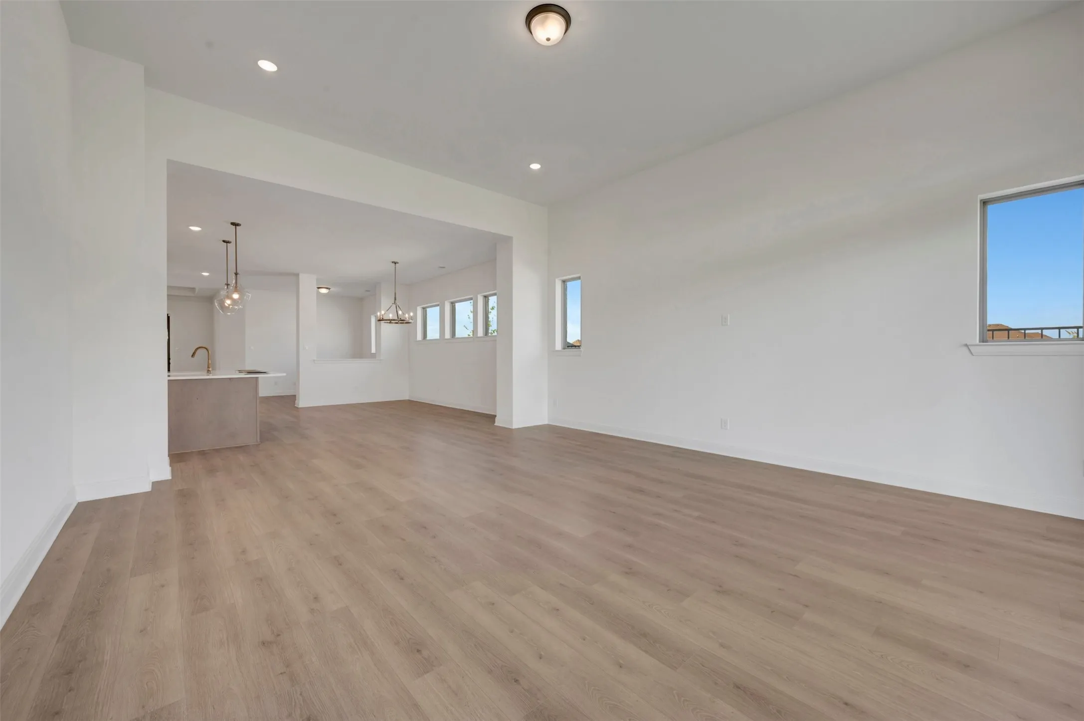 Open-concept living area featuring wood-finish flooring, recessed lighting, and bright white walls