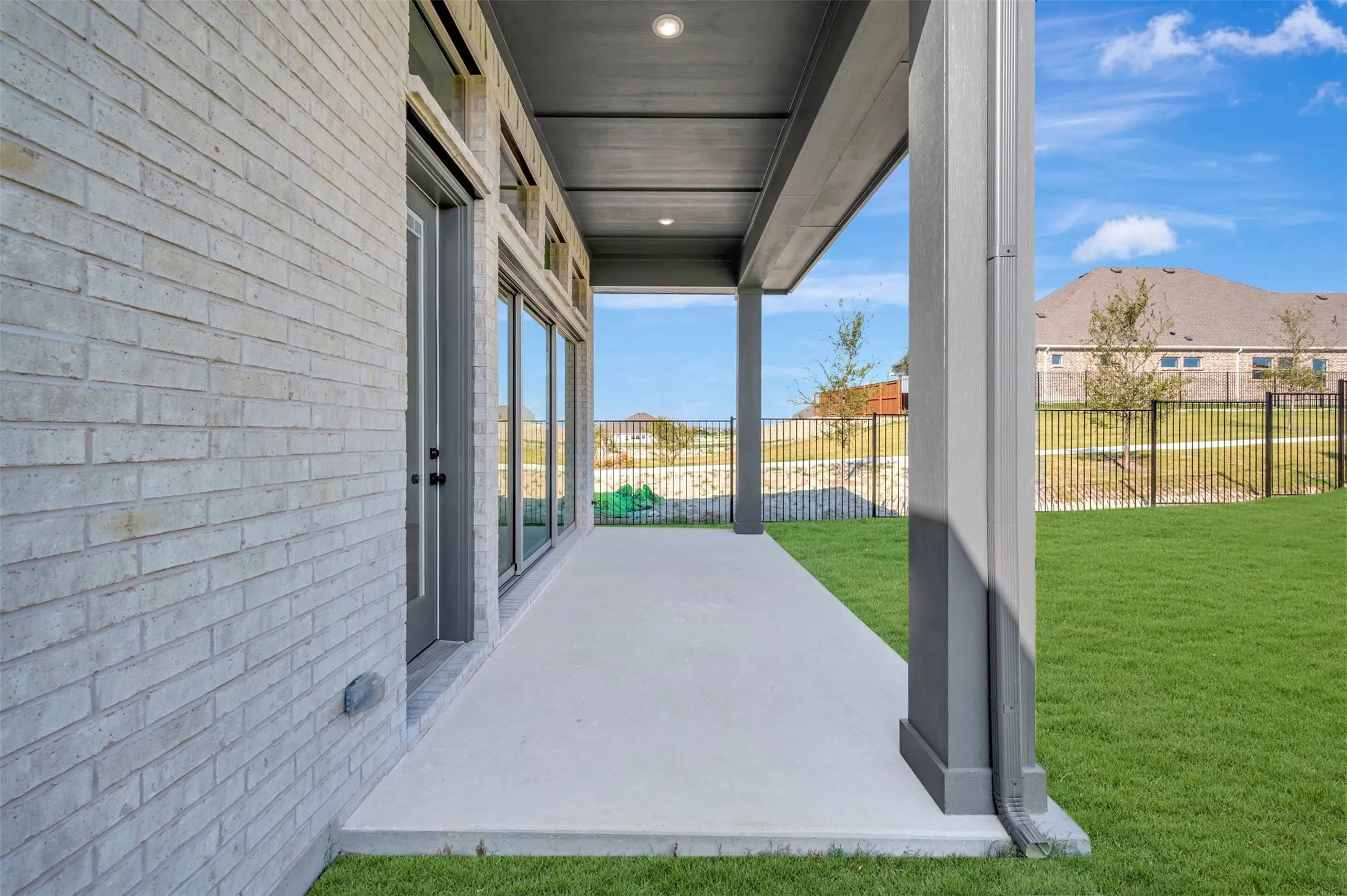 Covered concrete patio with recessed lighting, offering direct access to the backyard through glass sliding doors