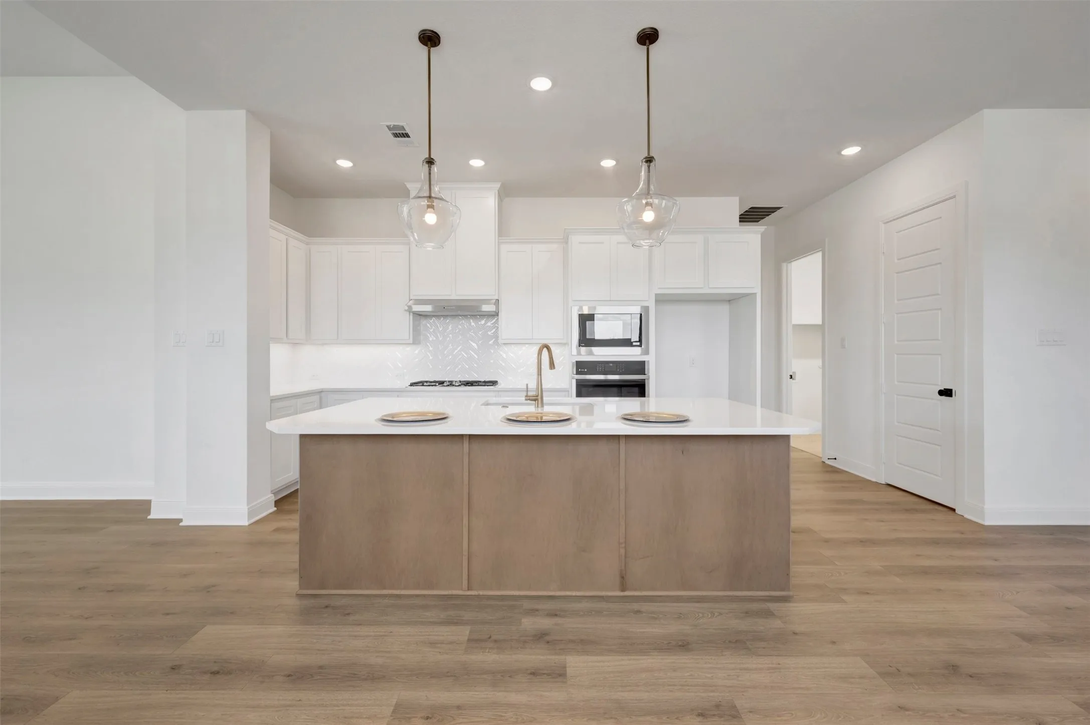 Contemporary kitchen with a central island featuring a light wood-finish base and a light-colored countertop