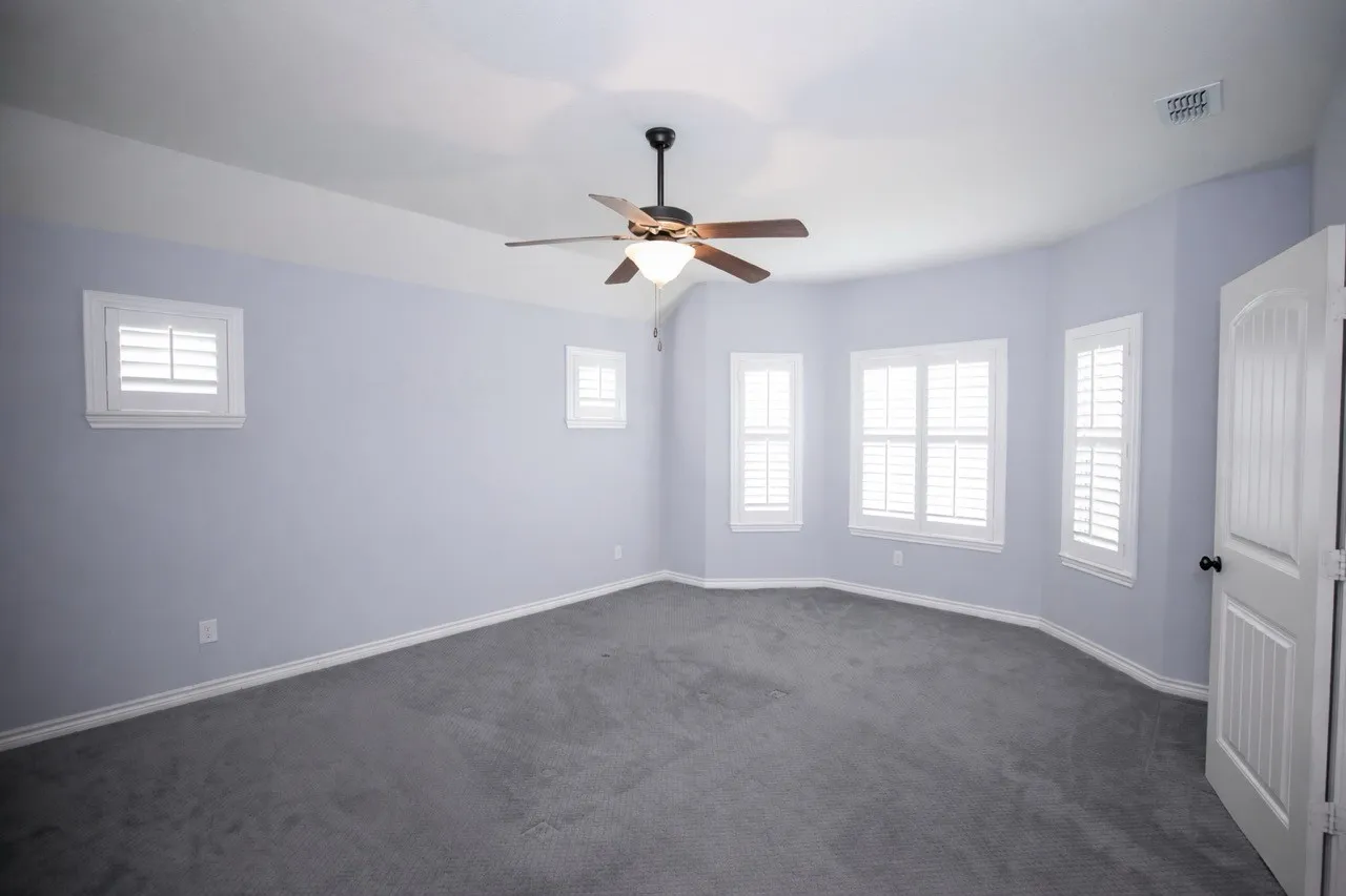 Unfurnished room featuring dark colored carpet and a ceiling fan