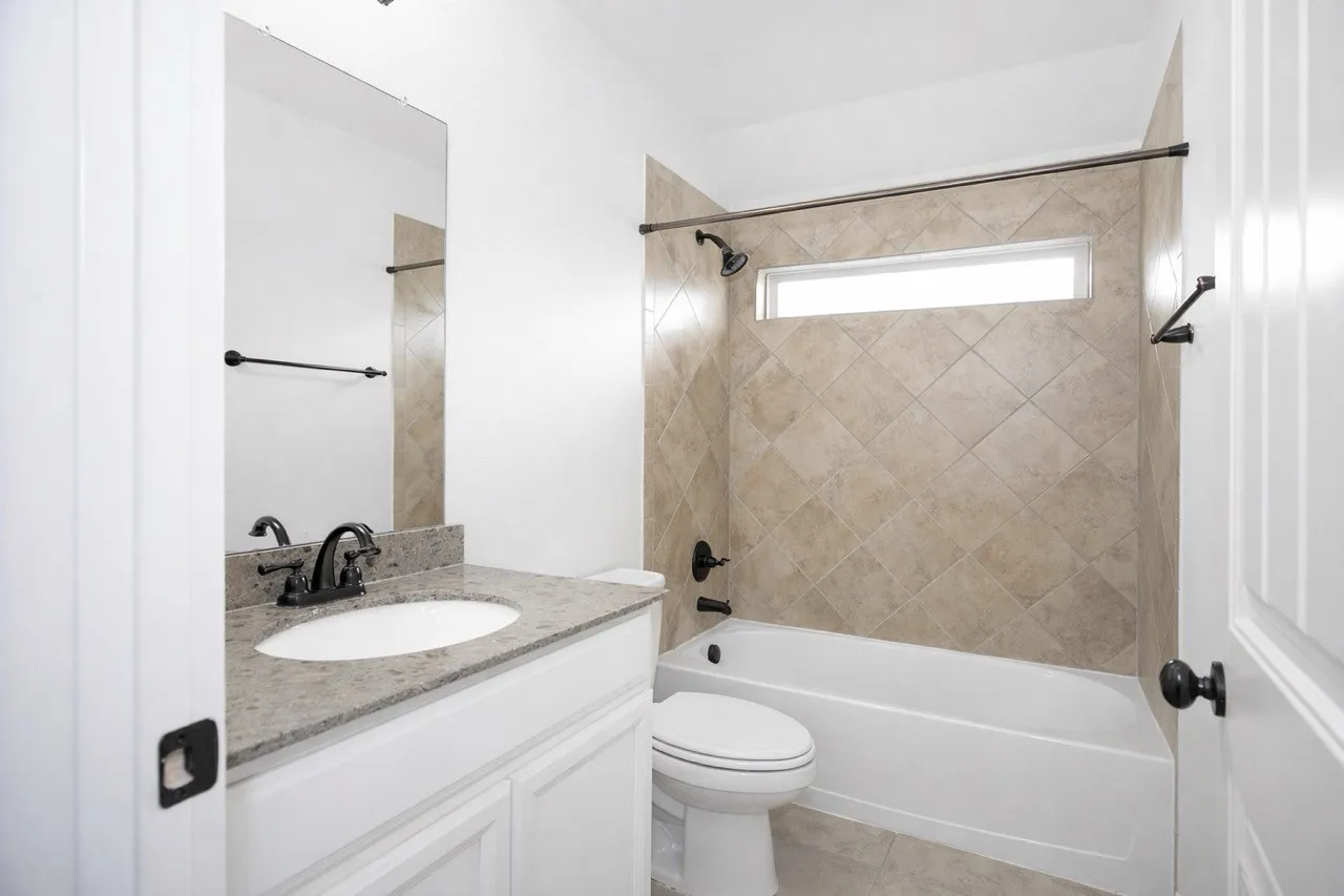 Virtual Staged  Full bath with vanity, washtub / shower combination, and light tile patterned flooring