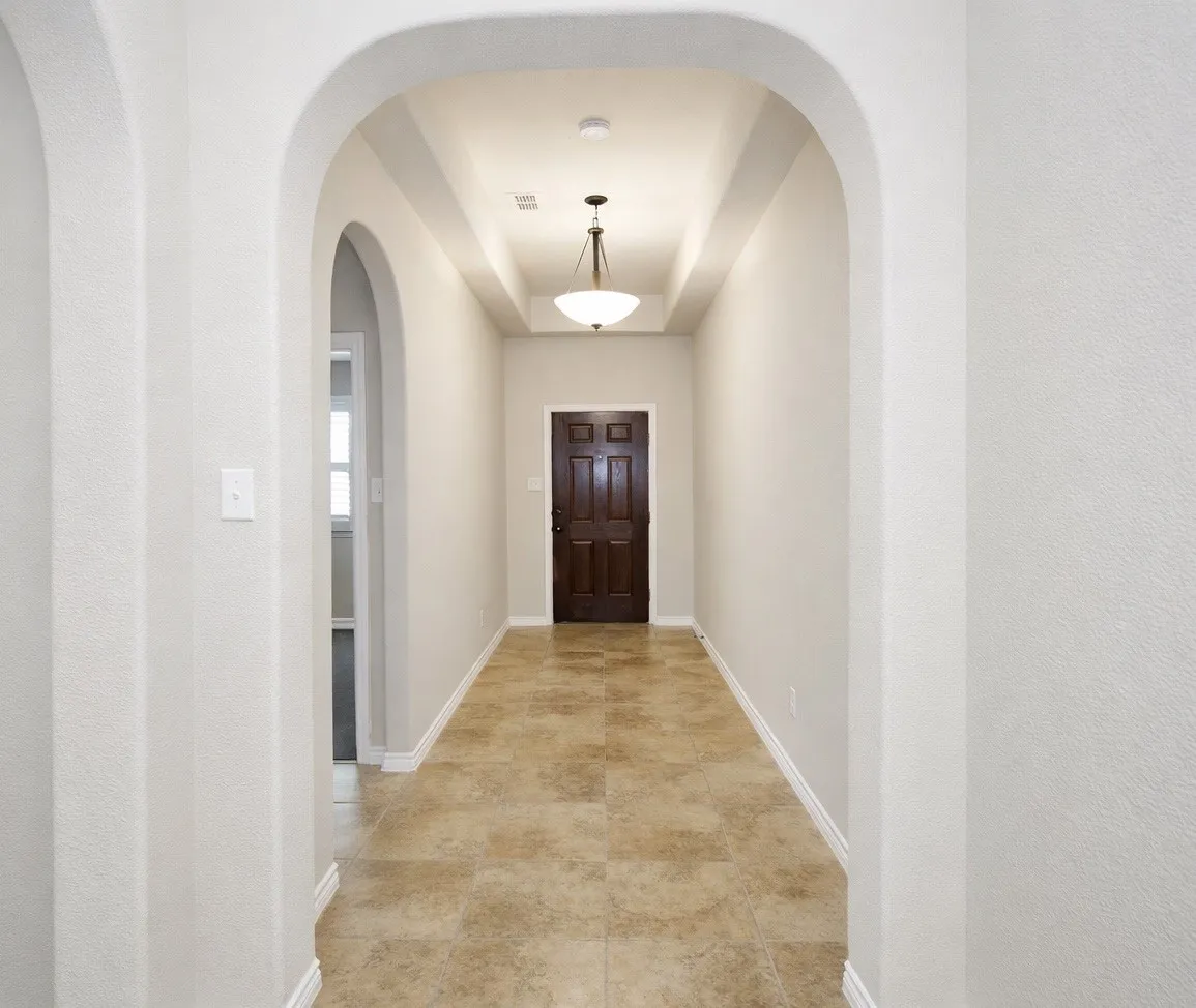 Doorway with a textured wall and a tray ceiling