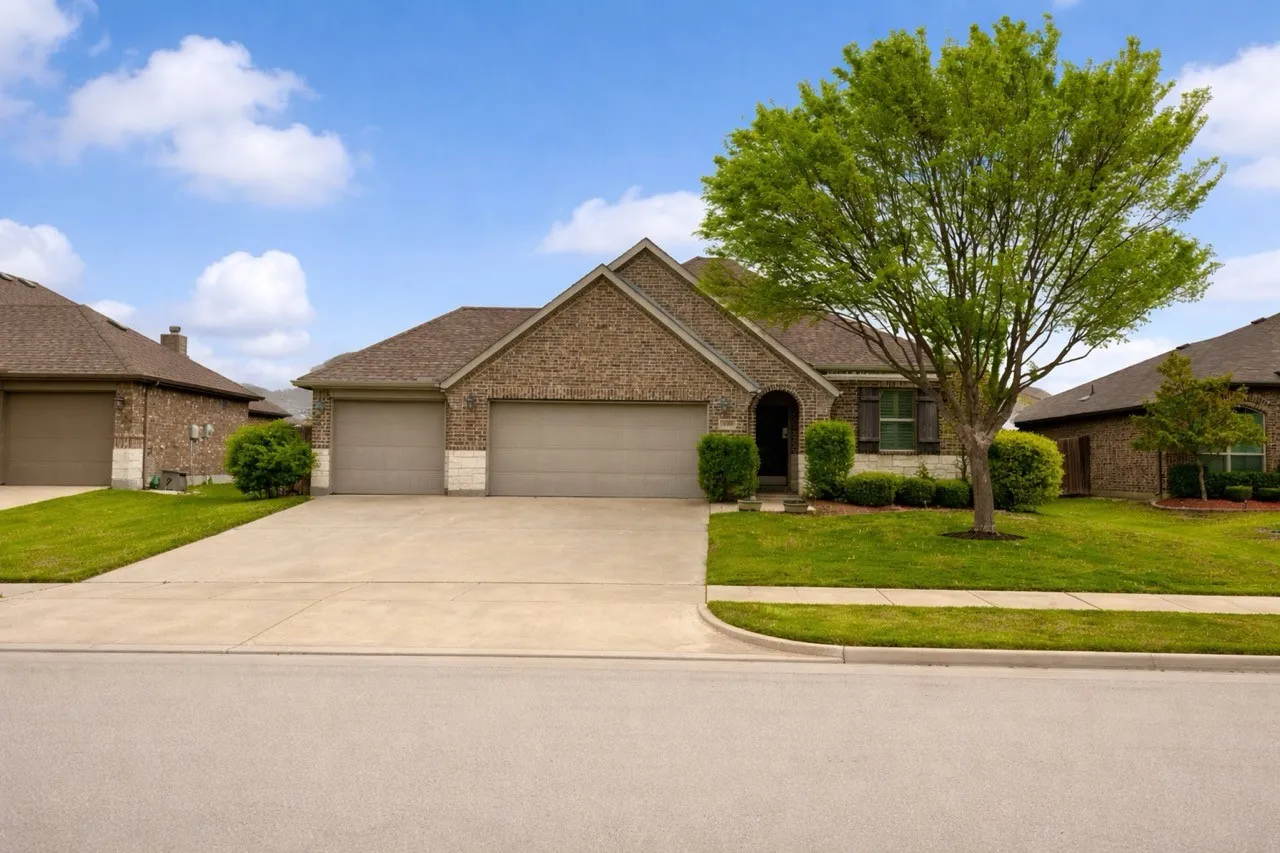 Ranch-style house featuring brick siding, a garage, a front lawn, and driveway