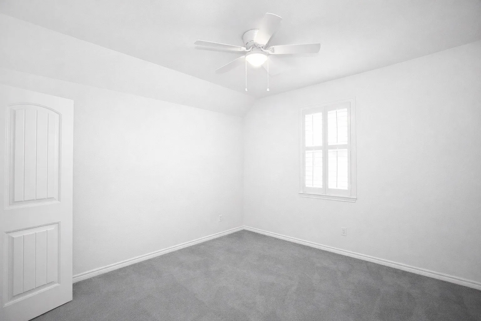 Empty room featuring vaulted ceiling, dark carpet, and a ceiling fan