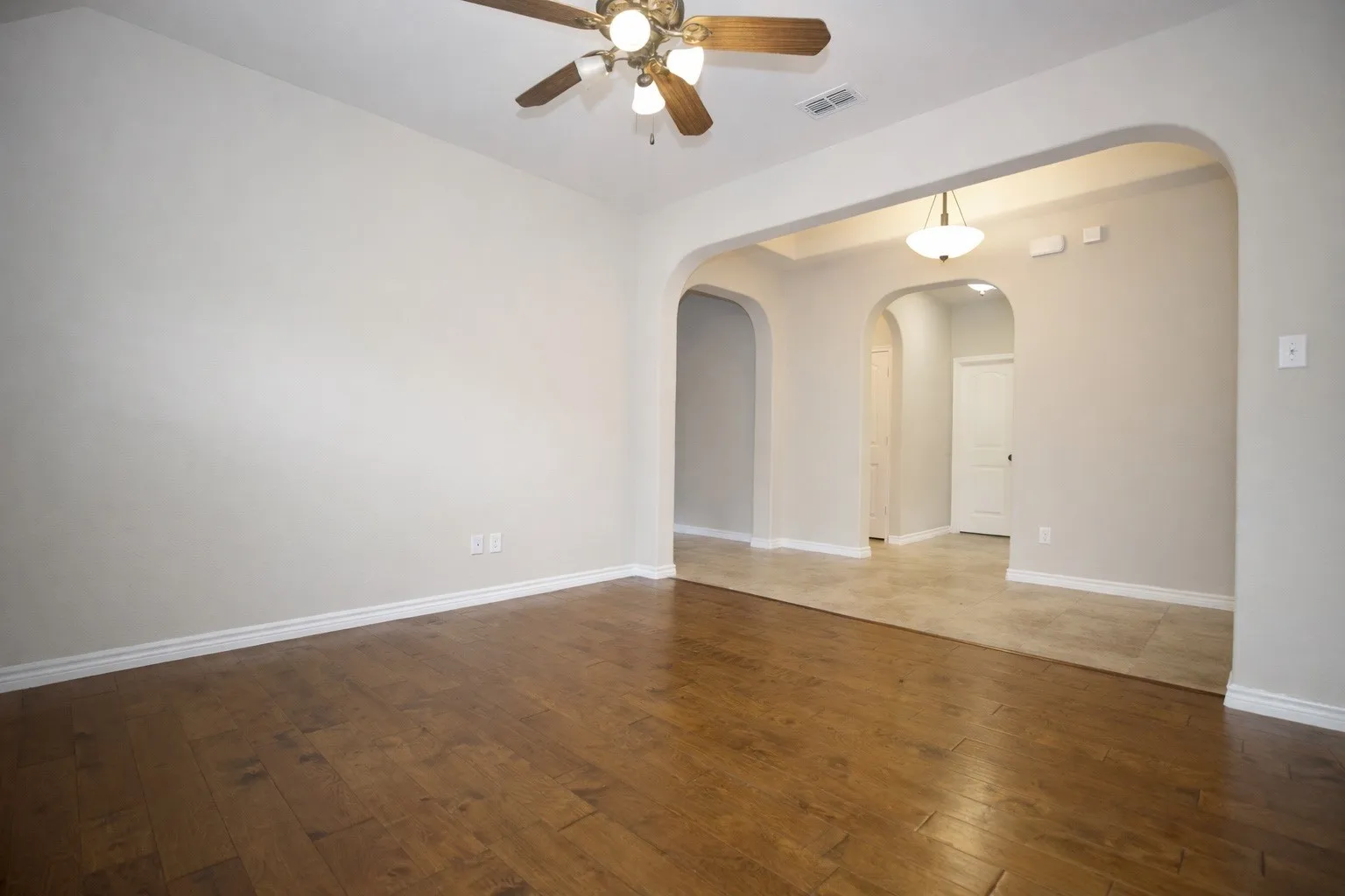 Empty room featuring ceiling fan and dark wood-type flooring