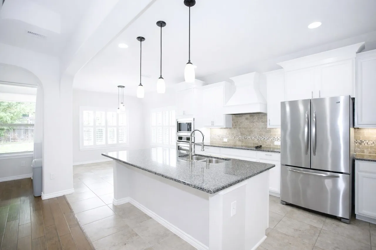 Kitchen featuring stainless steel appliances, white cabinets, dark stone countertops, and light tile patterned floors