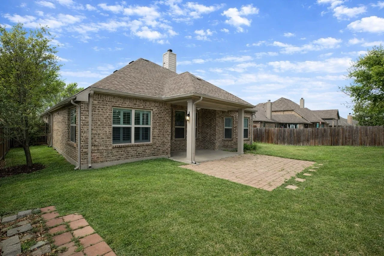 Back of property with a patio, brick siding, a fenced backyard, and a chimney