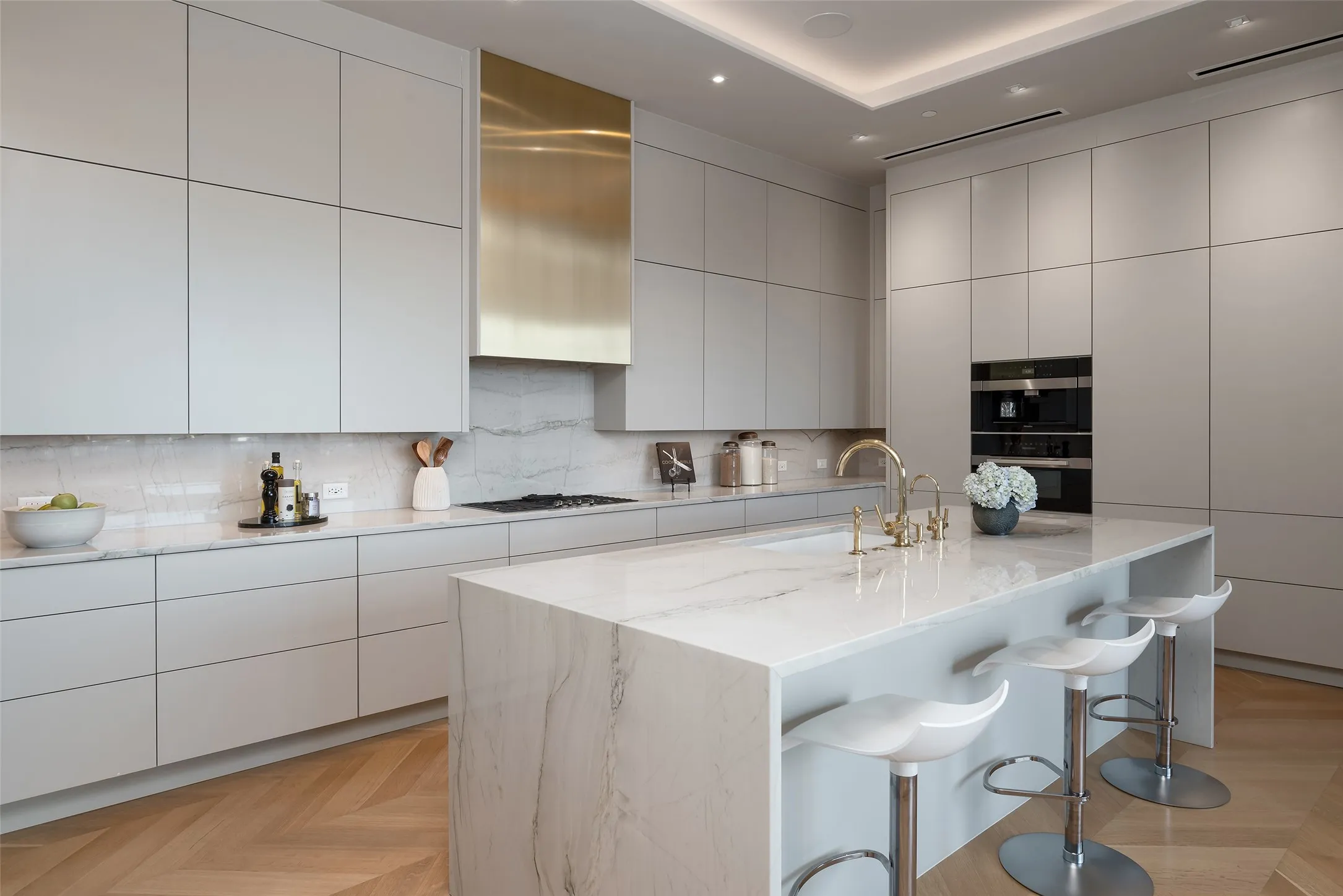 Kitchen with modern cabinets, parquet floors, light stone countertops, a breakfast bar area, and a kitchen island with sink