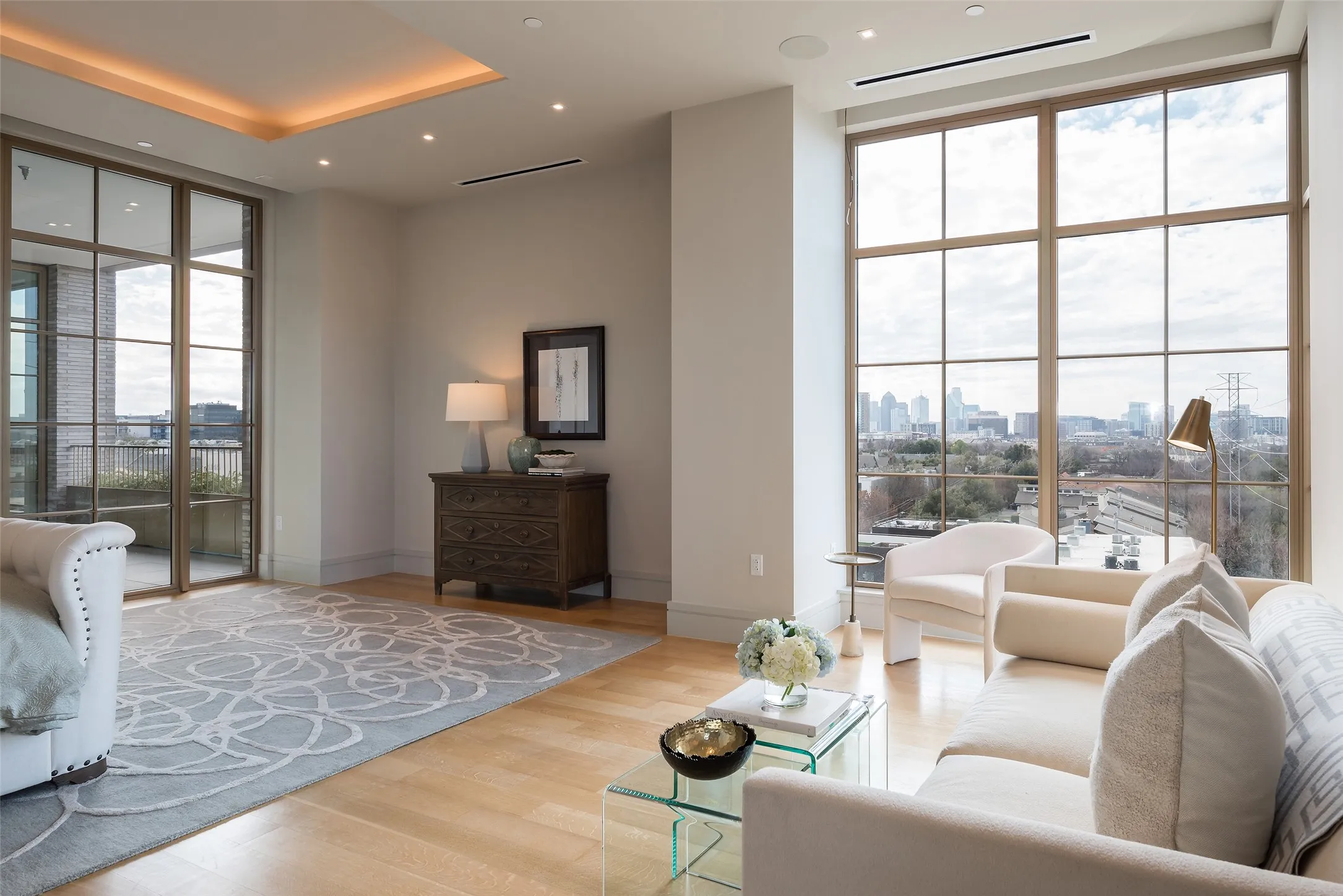Living room featuring floor to ceiling windows, wood finished floors, recessed lighting, a view of skyline, and a tray ceiling