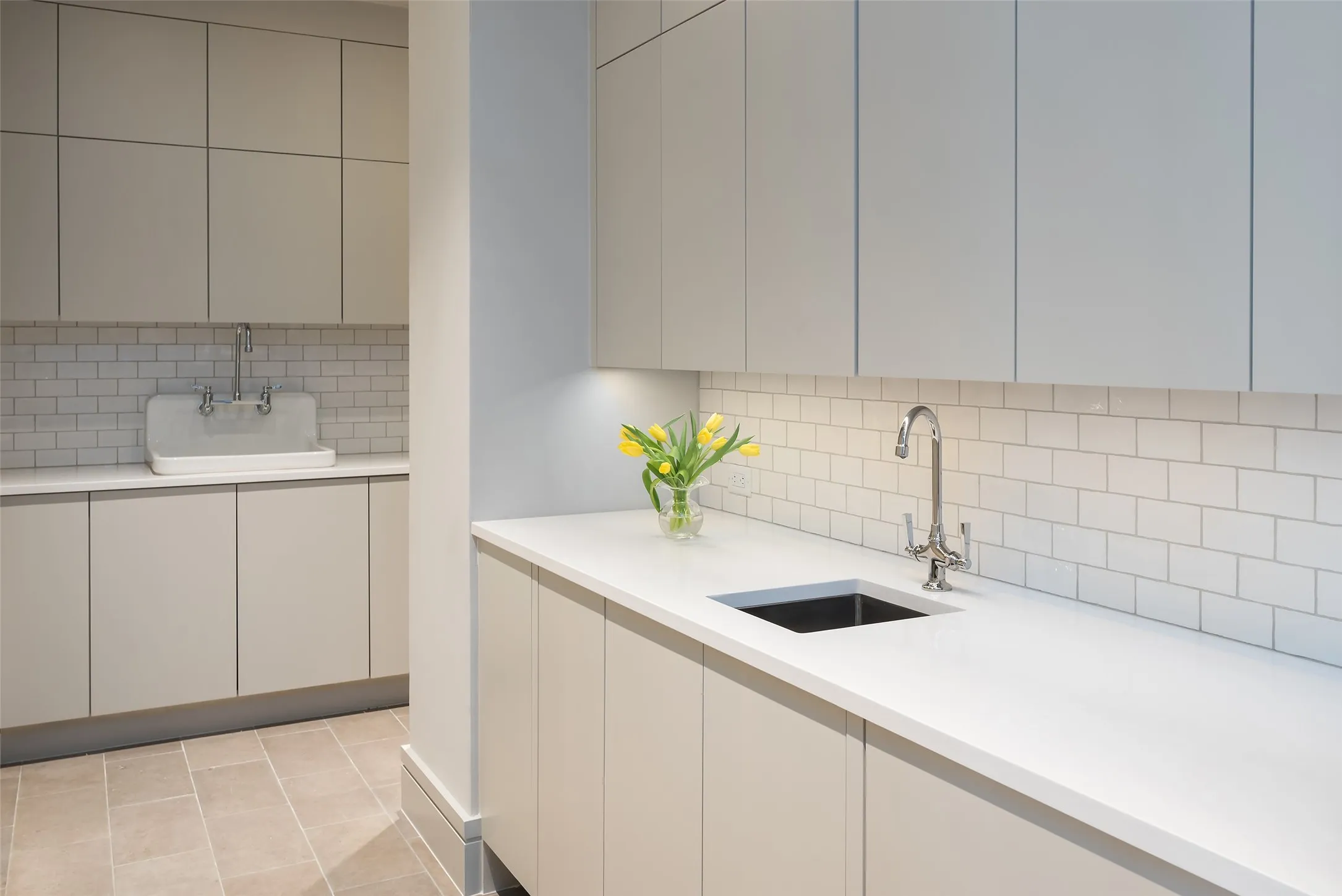 Kitchen featuring modern cabinets, backsplash, light stone counters, and white cabinets