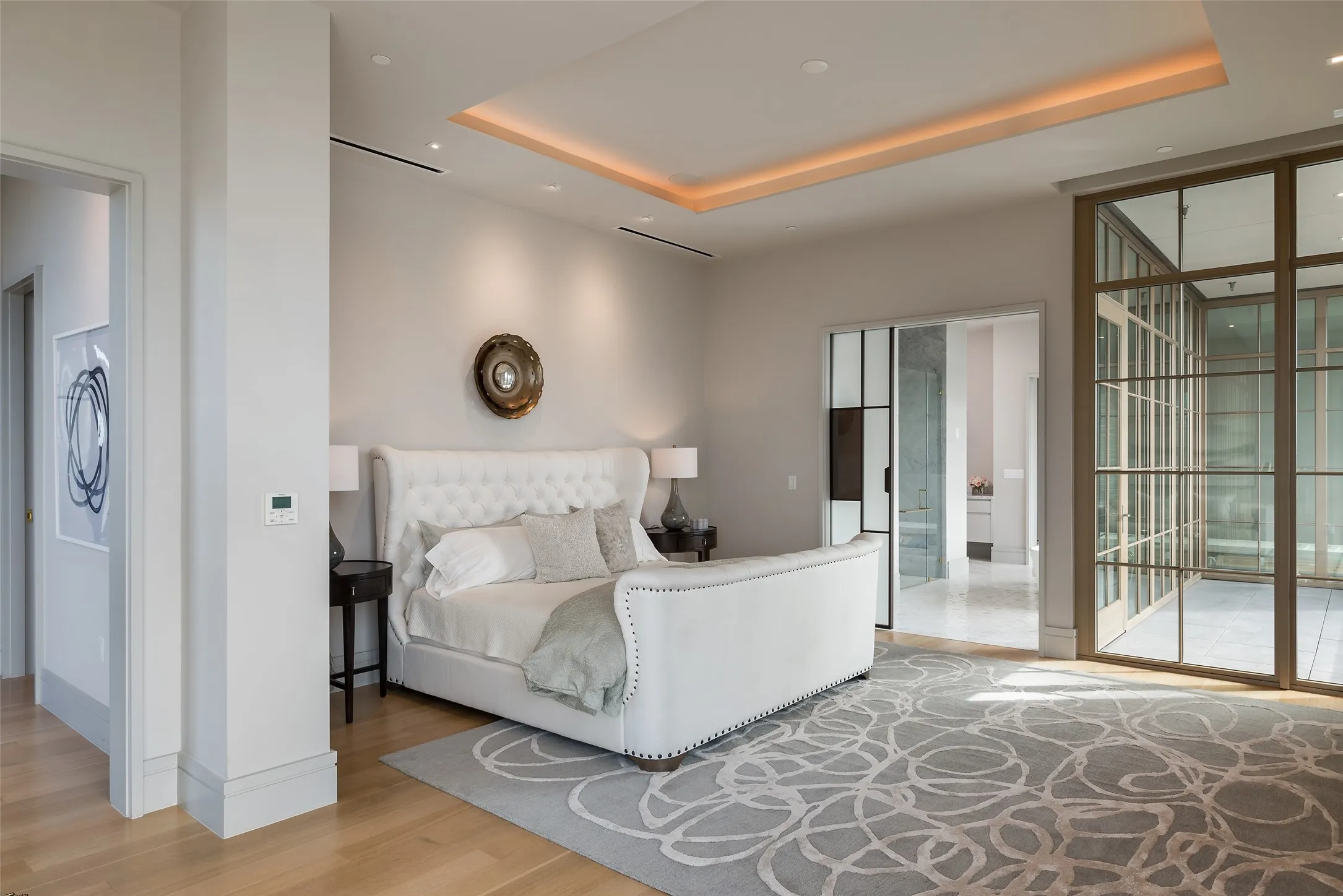 Bedroom featuring light wood finished floors, a tray ceiling, access to exterior, recessed lighting, and expansive windows