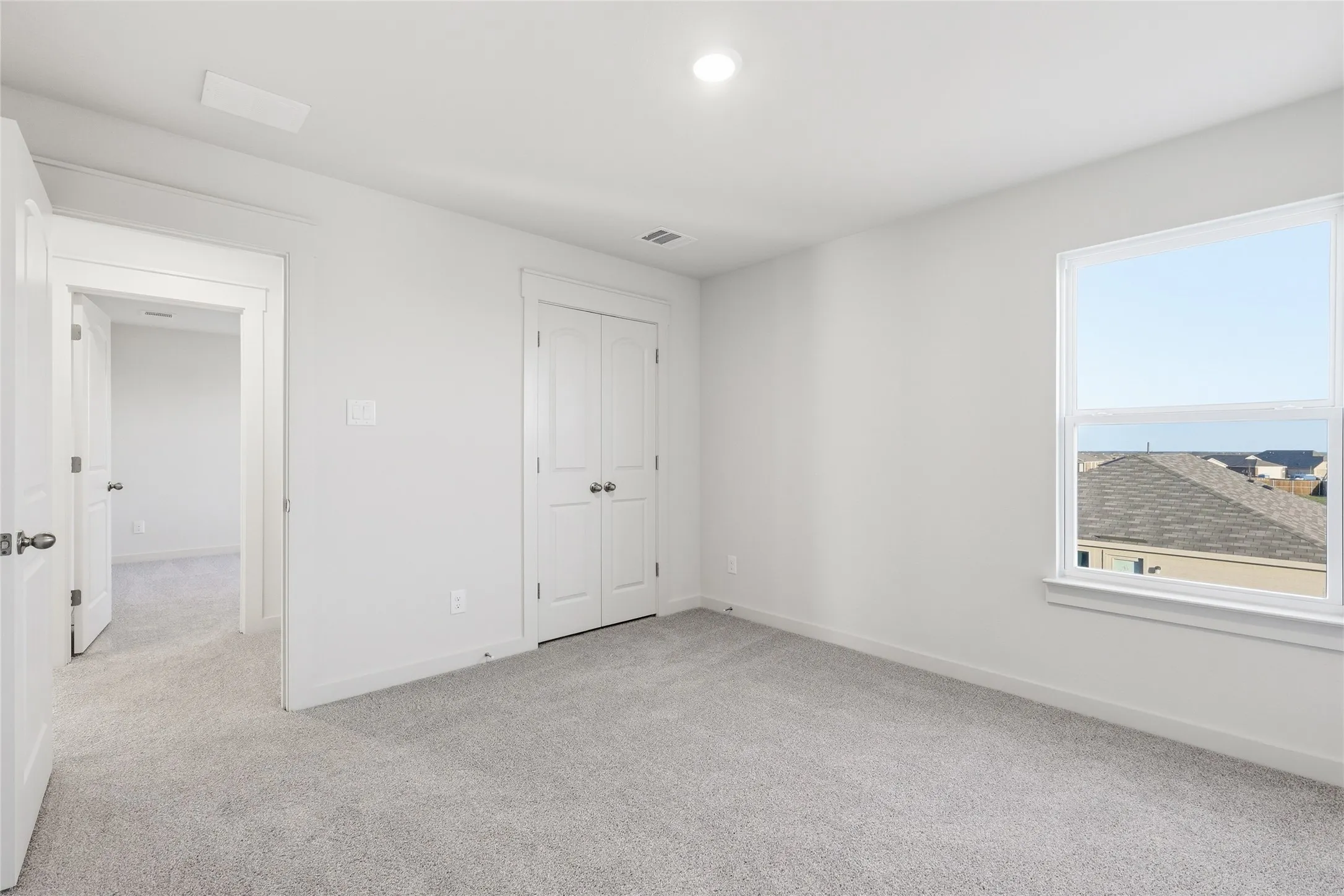 Carpeted interior room with a window, recessed lighting, and a bi-fold closet