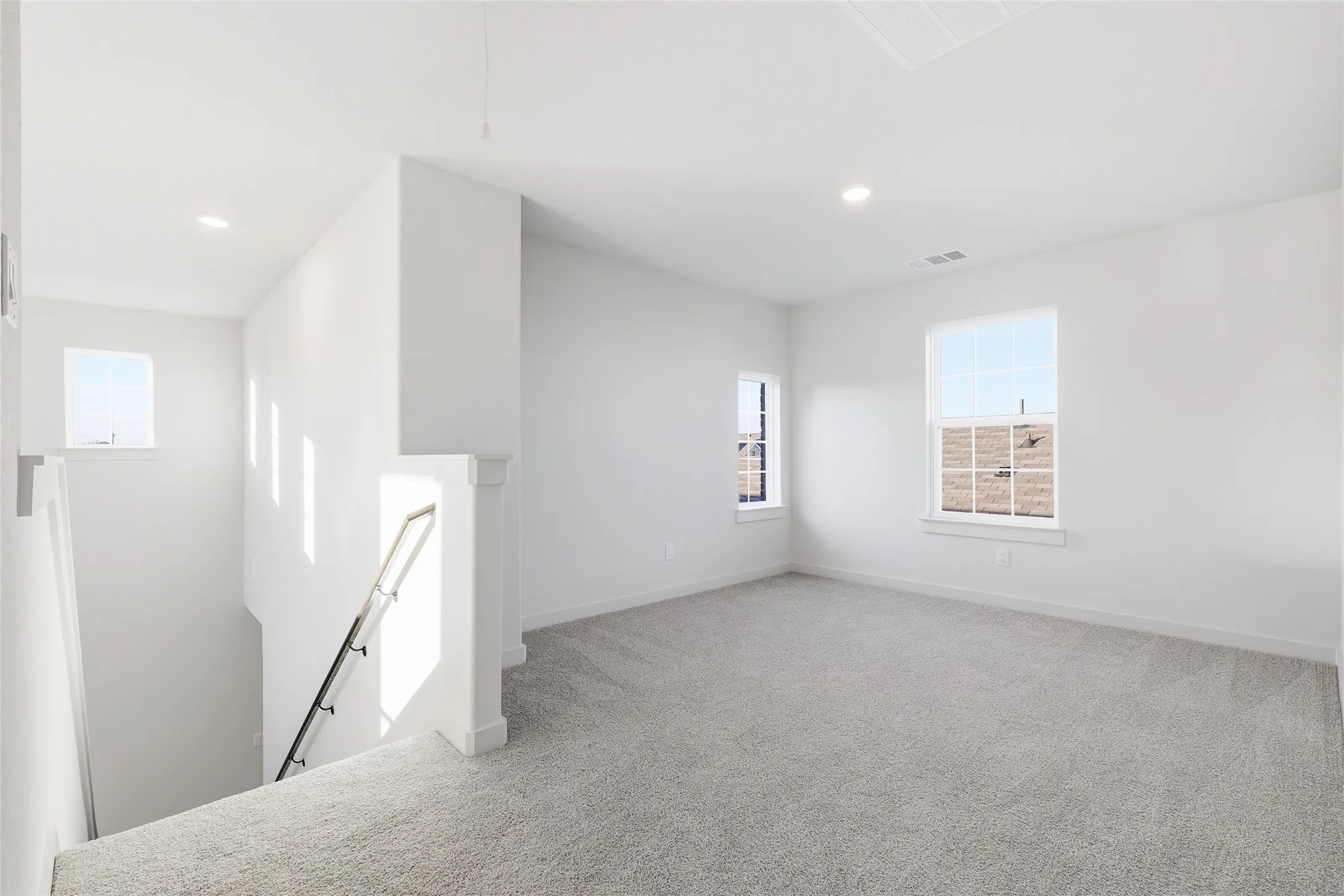 Carpeted loft area featuring recessed lighting and multiple windows