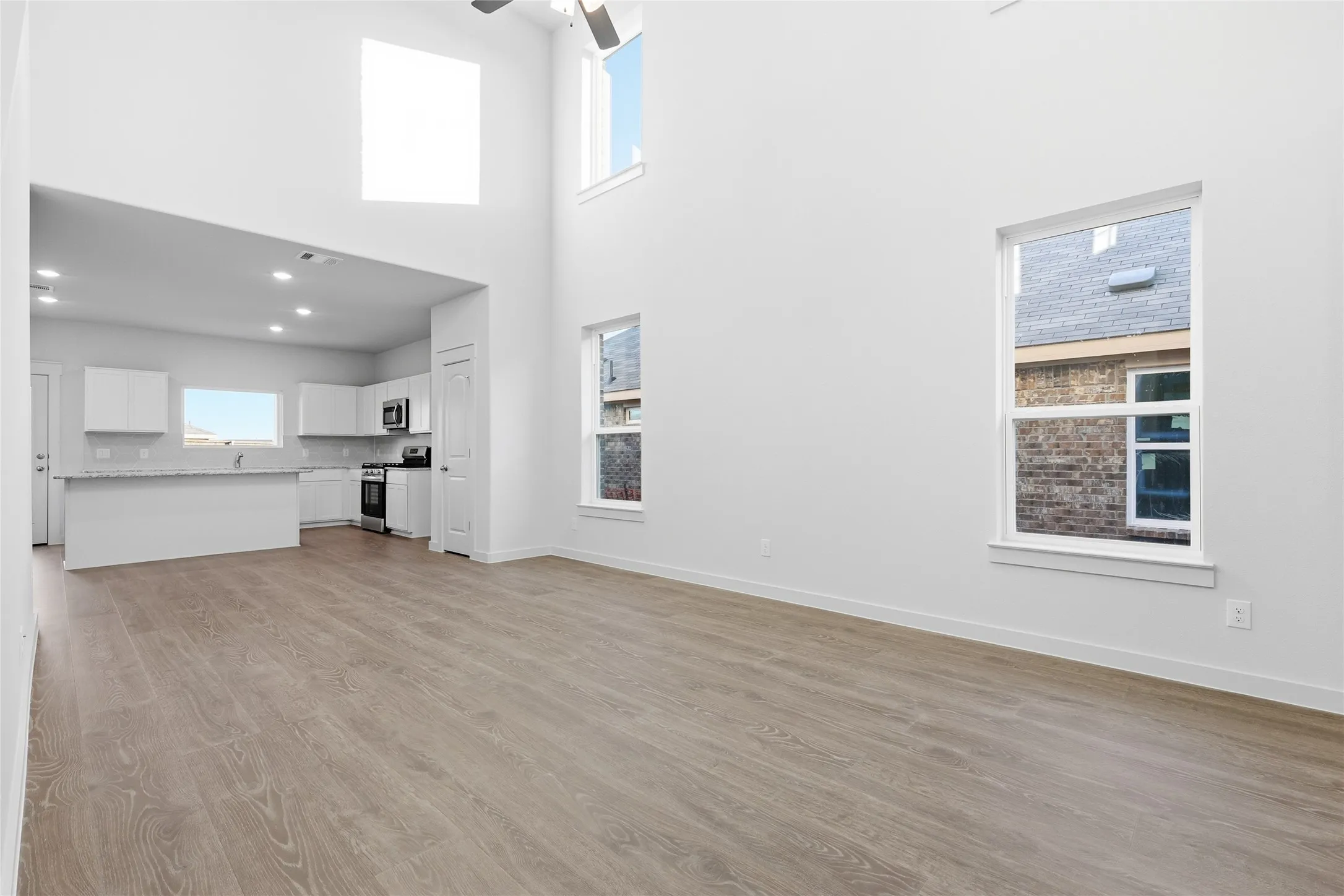 Open-concept living space featuring high ceilings, wood-finish flooring, and multiple windows