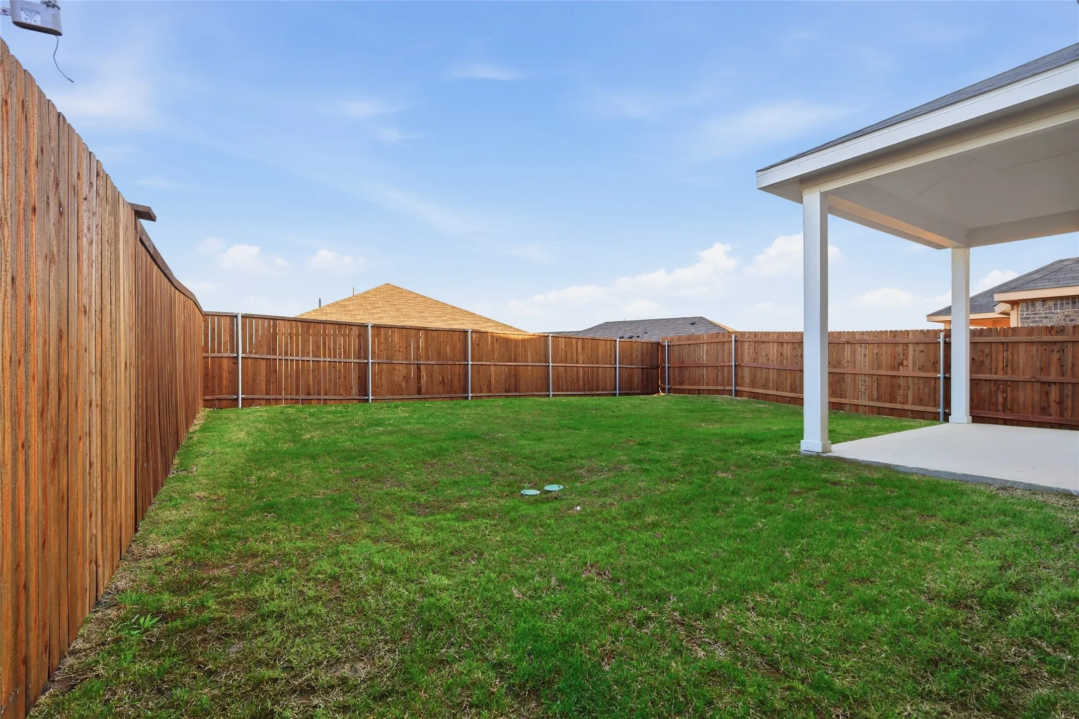 Spacious backyard featuring a covered patio, a full privacy fence, and a generous lawn area