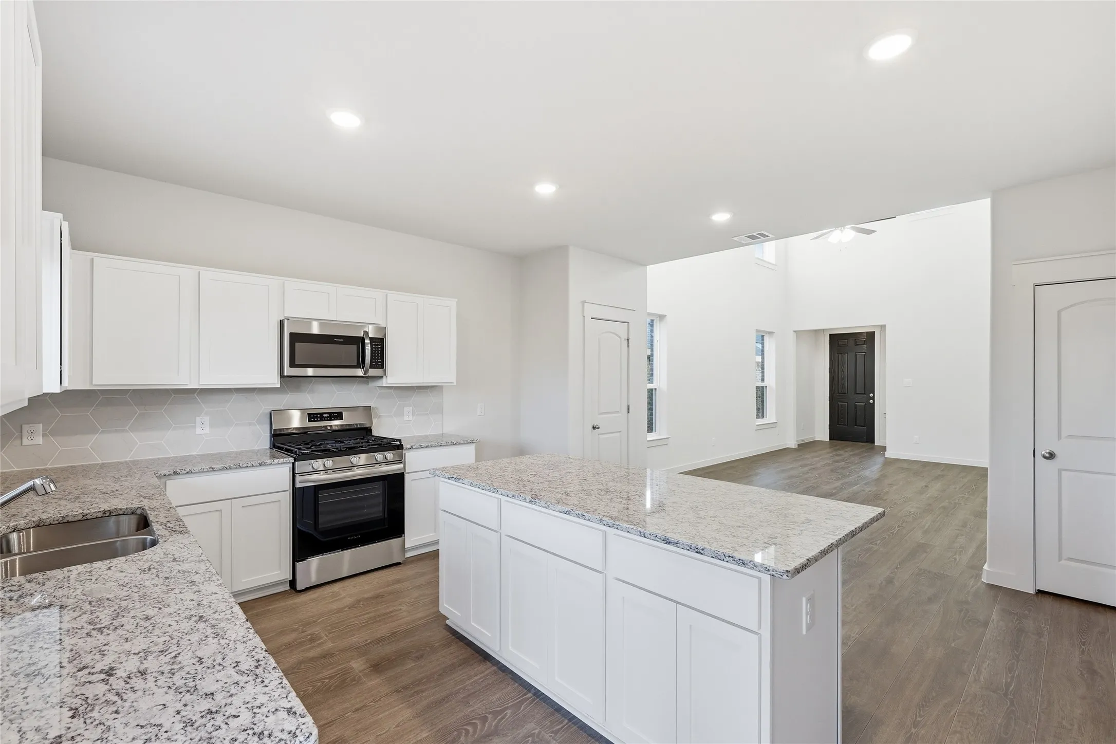 Kitchen featuring white cabinetry, light-colored countertops, stainless steel appliances, and a hexagon-patterned backsplash