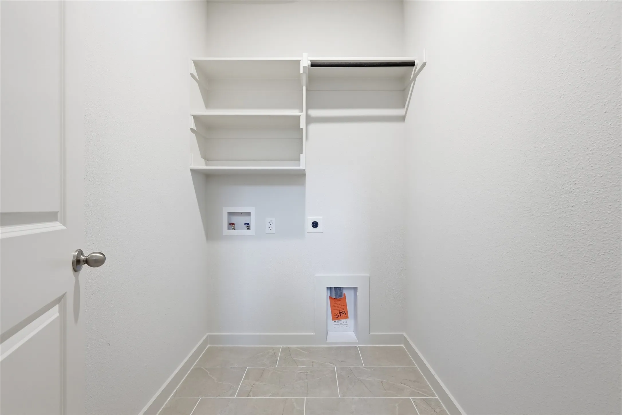 Dedicated laundry area featuring built-in shelving, a hanging rod, tile flooring, and utility hookups