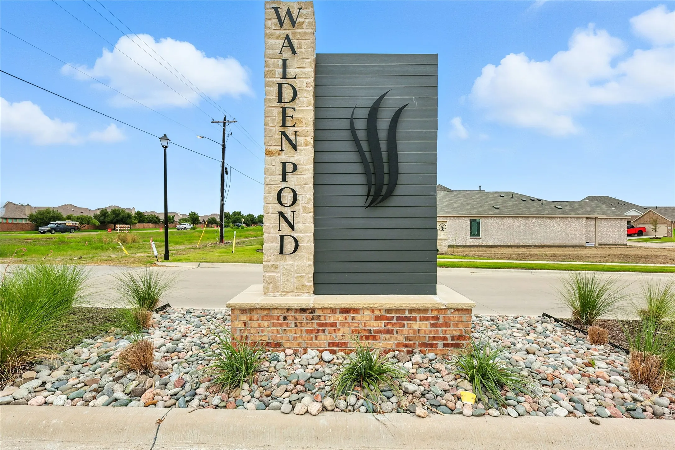 Community entrance sign featuring stone cladding, horizontal siding, and a decorative emblem