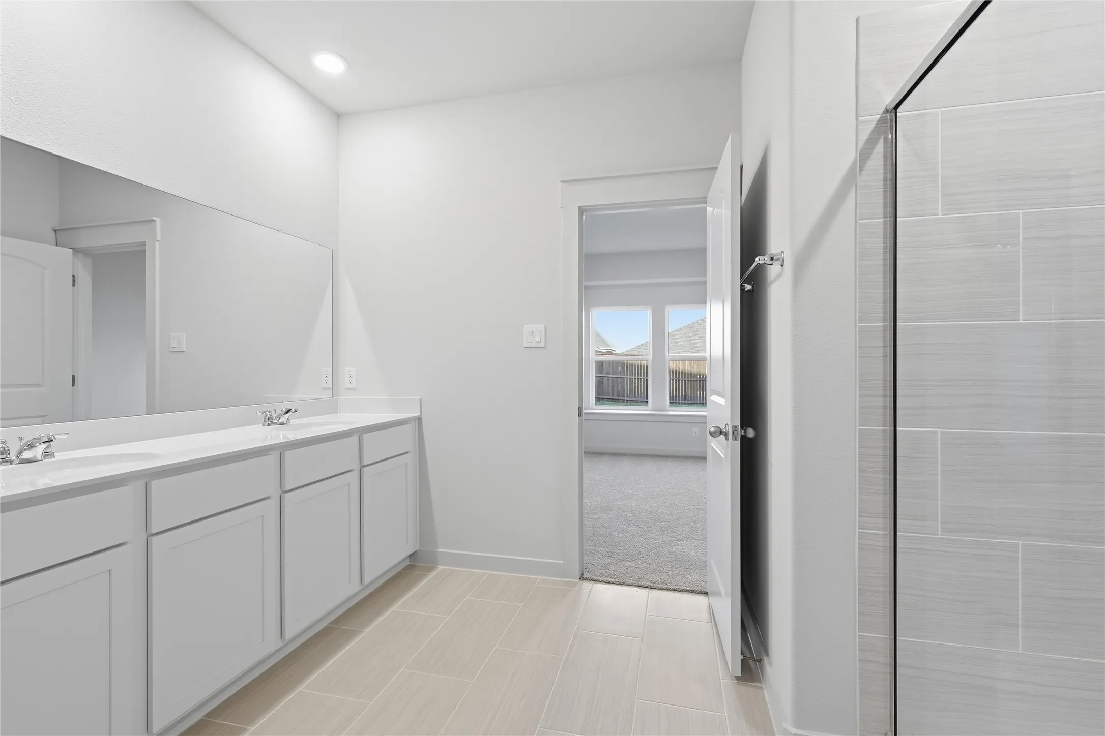 Bathroom featuring a dual vanity with white cabinetry and countertops, a large mirror, and recessed lighting