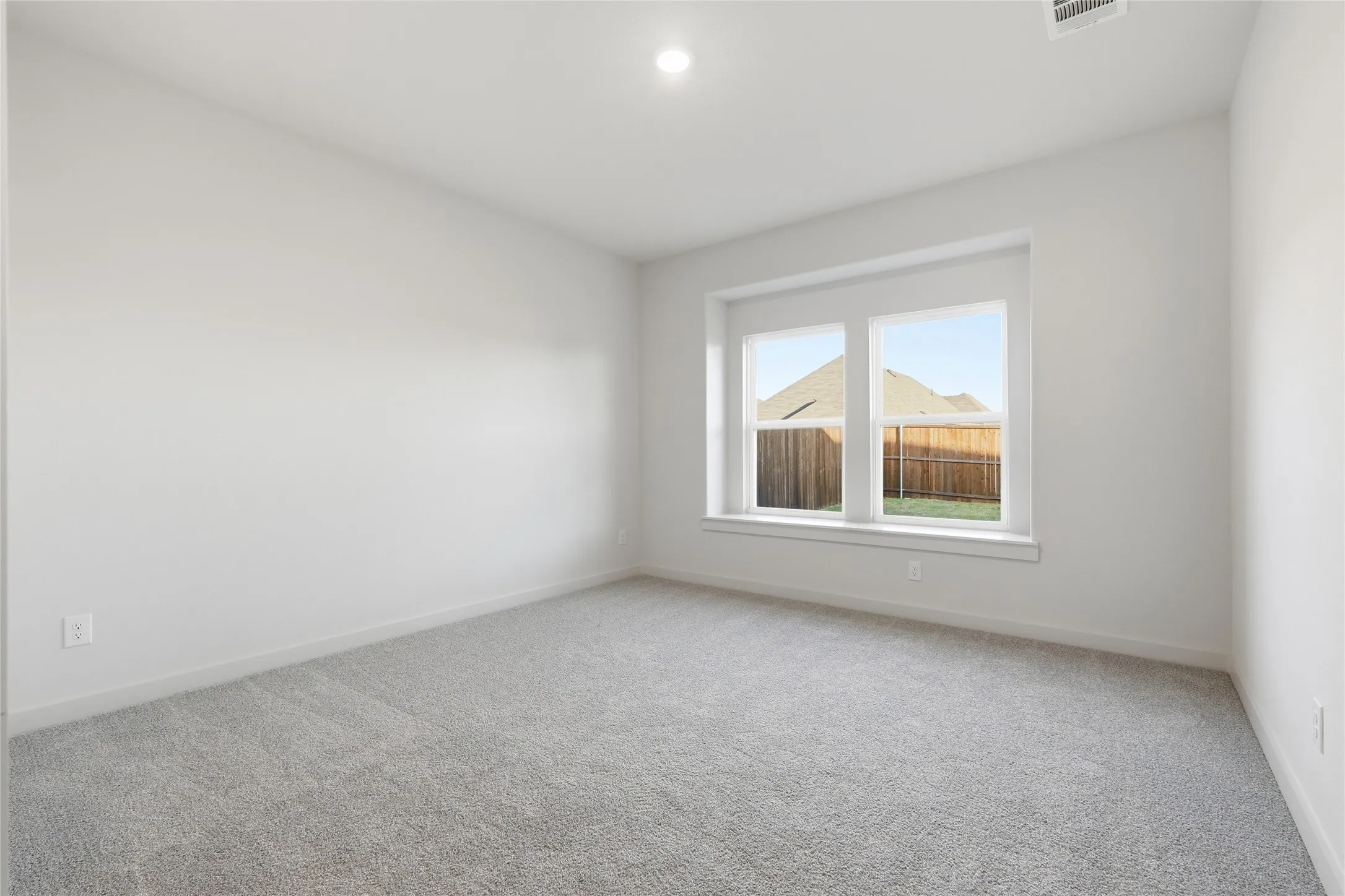 Neutral-toned carpeting and walls complement the natural light entering through the large window