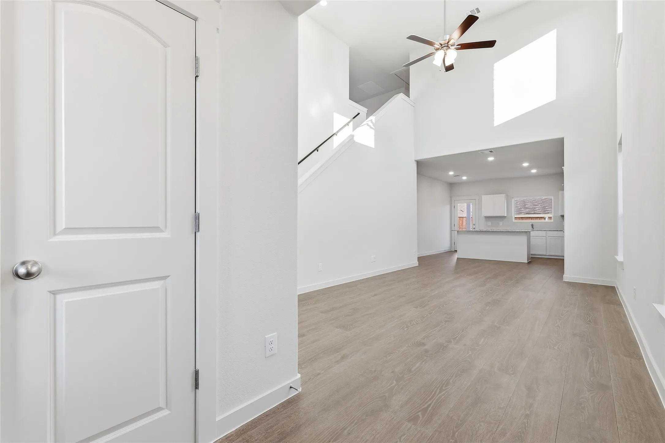 Open-concept living space featuring high ceilings, wood-finish flooring, a ceiling fan, and recessed lighting