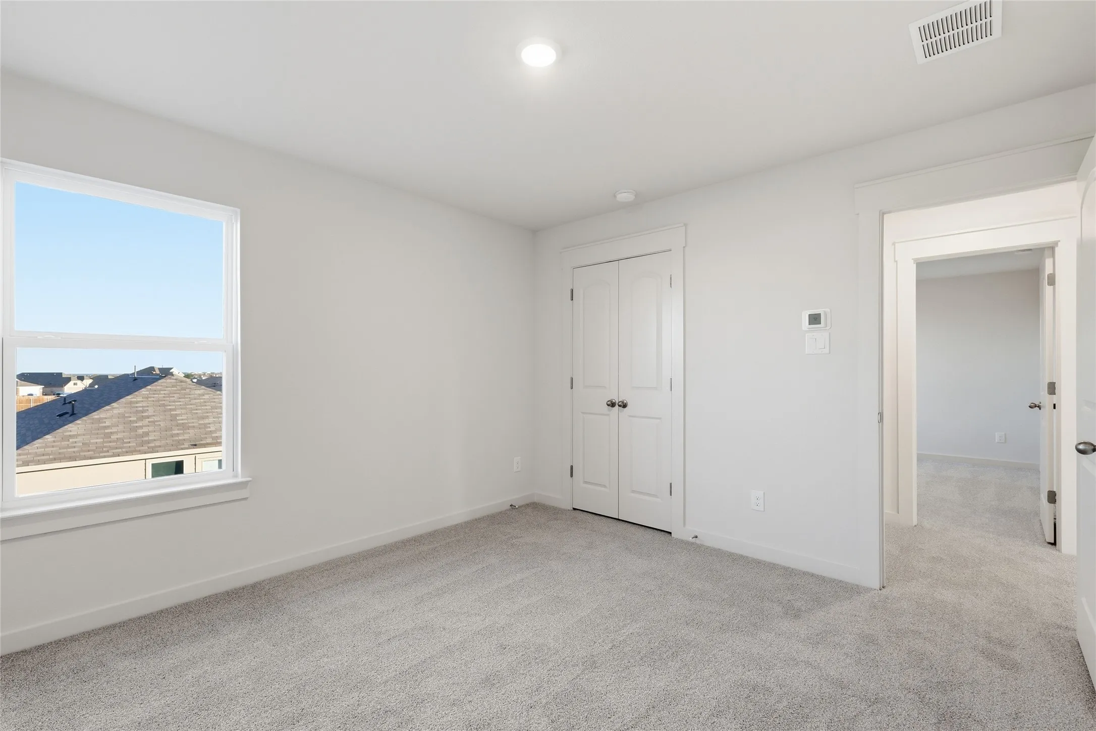 Carpeted room featuring a white-framed window, double-door closet, recessed lighting, and a white baseboard trim
