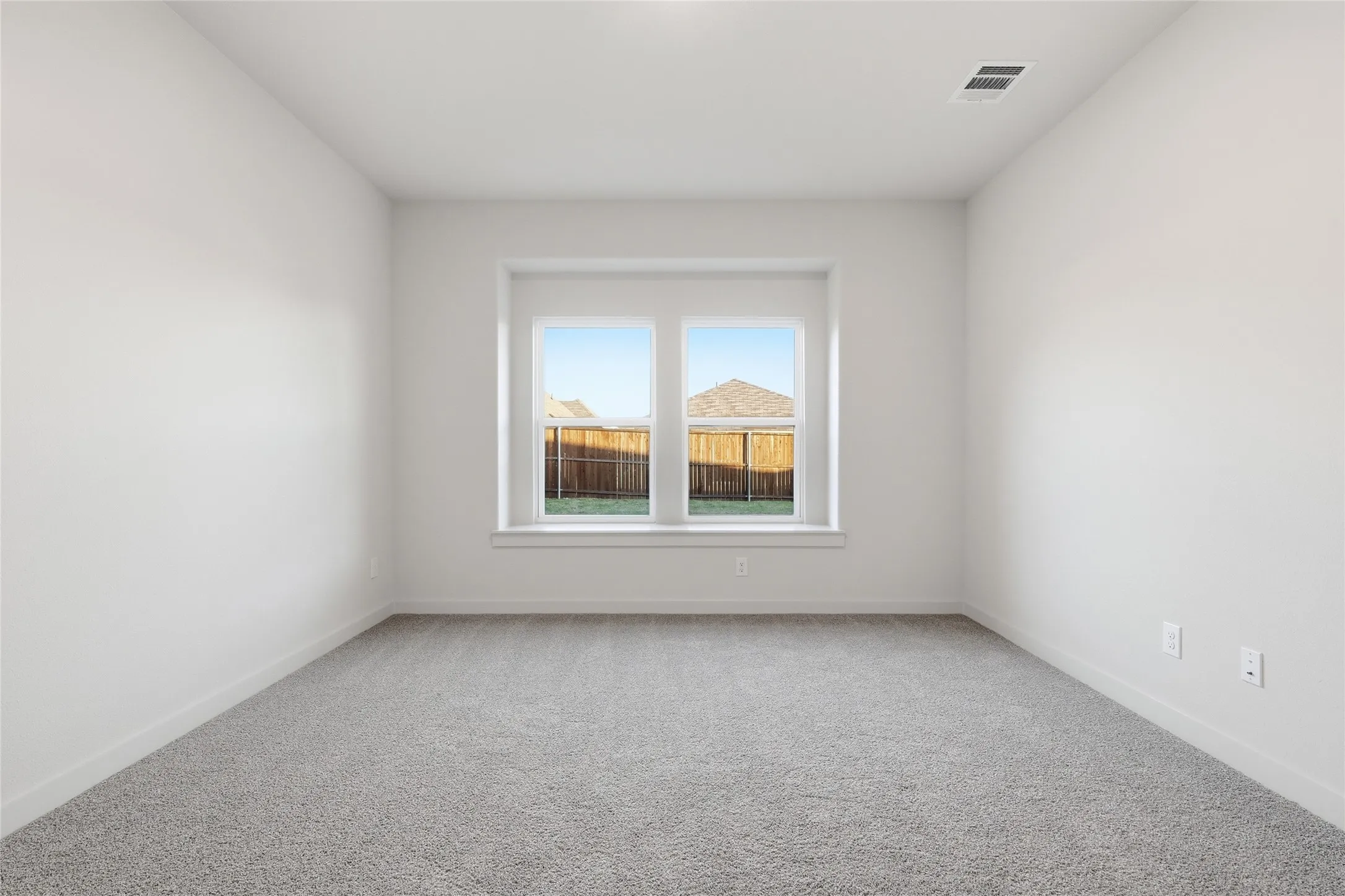 Spacious interior room with light gray carpeting and white painted walls