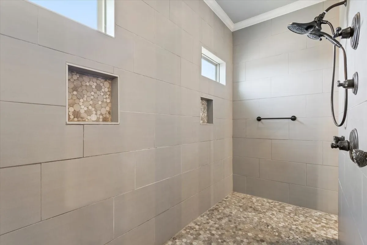 Full bath featuring a tile shower and ornamental molding