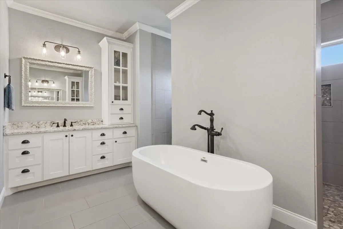 Full bathroom with vanity, a freestanding bath, light tile patterned floors, crown molding, and walk in shower