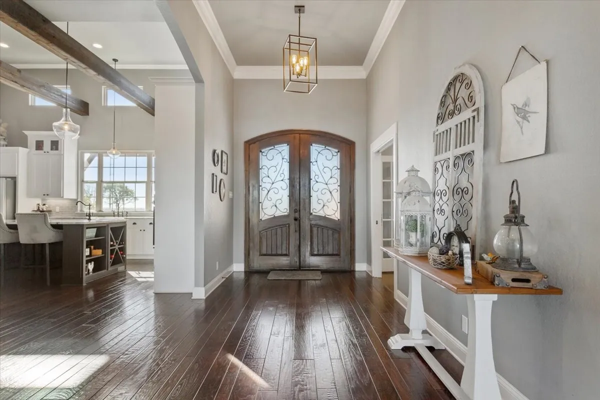 Entrance foyer with ornamental molding, a high ceiling, dark wood-style flooring, french doors, and a chandelier