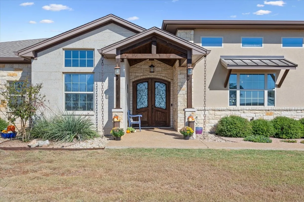 View of front of property featuring stone siding, a front yard, a standing seam roof, and french doors