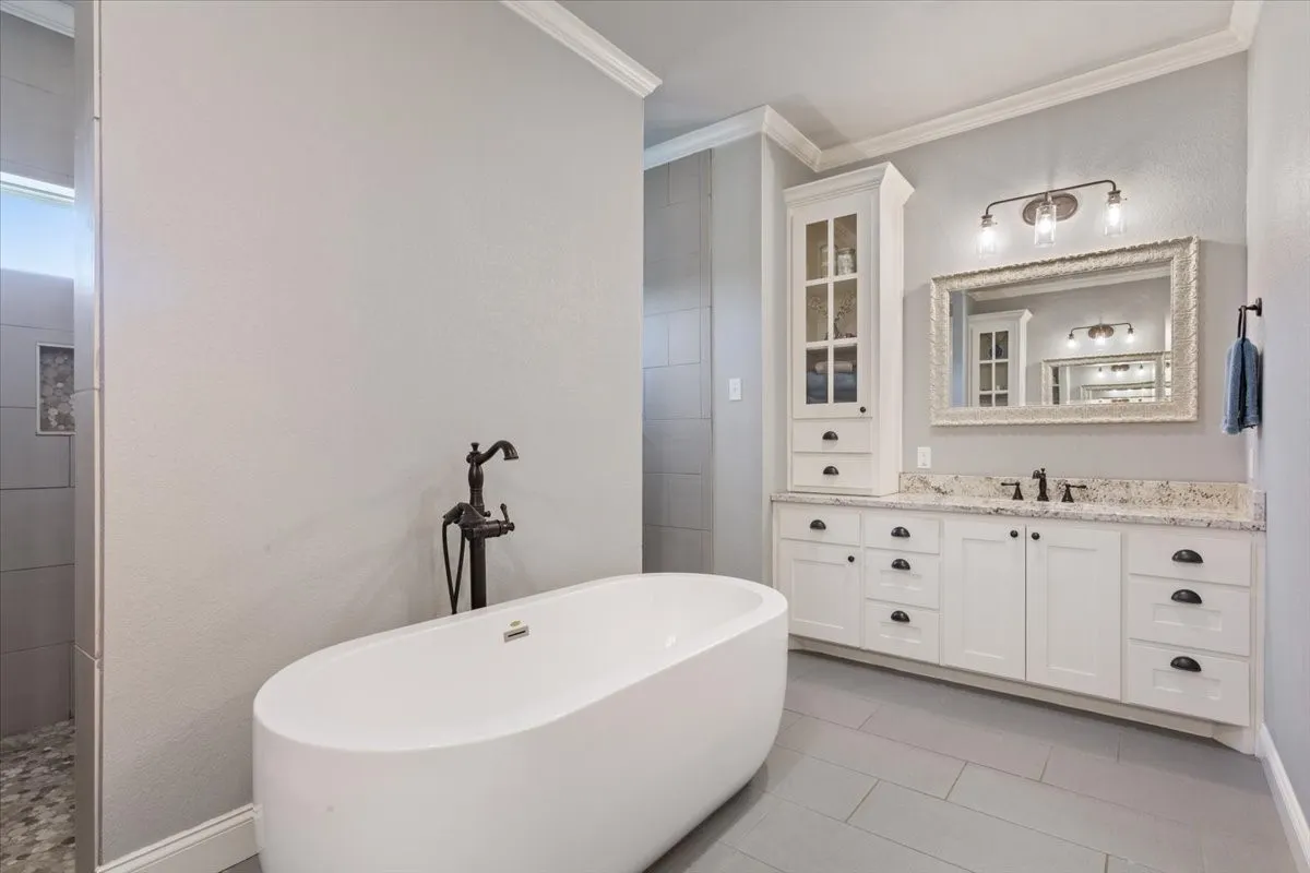 Bathroom featuring vanity, crown molding, a soaking tub, light tile patterned flooring, and a walk in shower