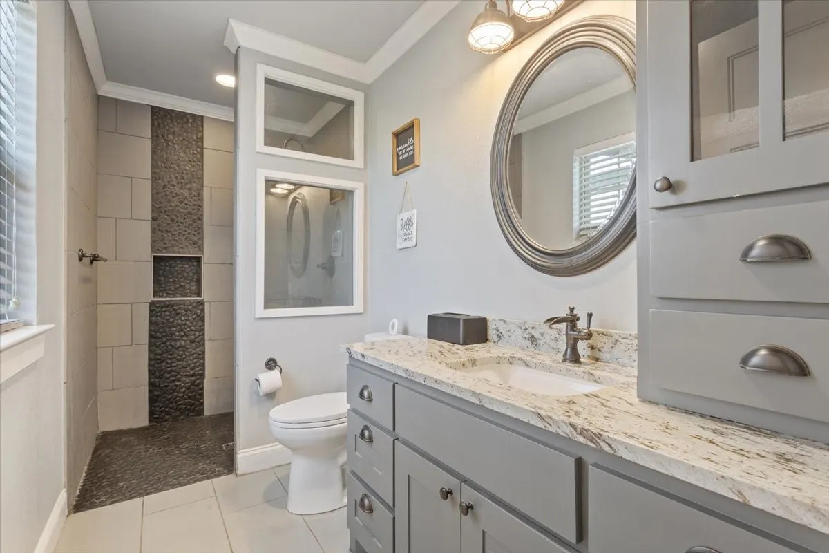 Full bathroom with vanity, crown molding, walk in shower, and light tile patterned floors