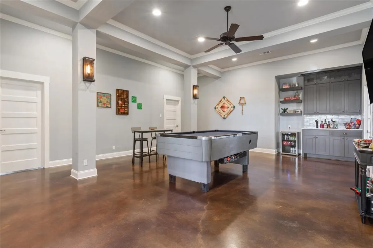 Game room with a bar, concrete floors, ceiling fan, ornamental molding, and recessed lighting