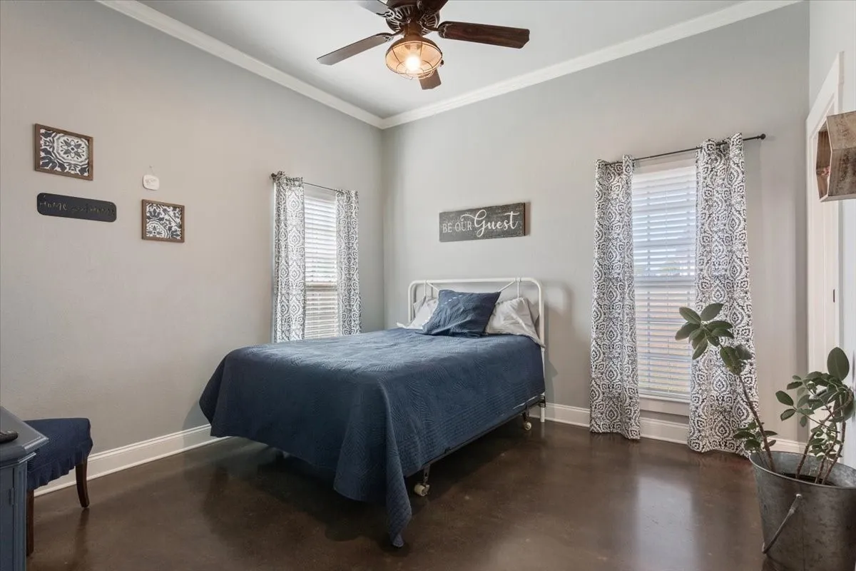 Bedroom featuring crown molding, multiple windows, ceiling fan, and concrete floors