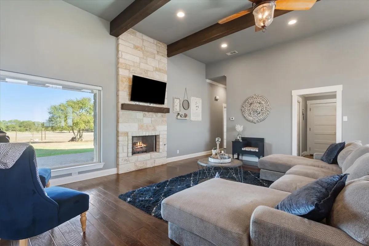Living room featuring a stone fireplace, wood-type flooring, ceiling fan, and recessed lighting
