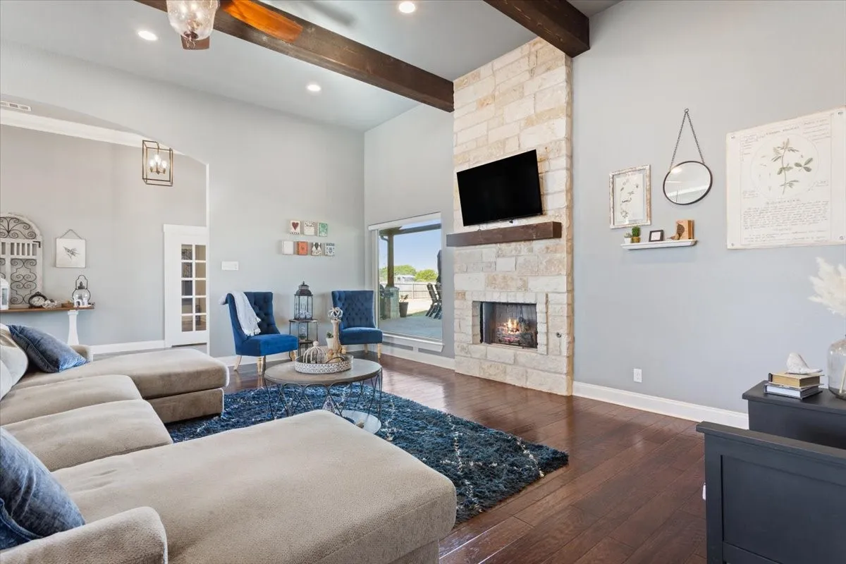 Living area with dark wood-style flooring, a stone fireplace, a ceiling fan, and recessed lighting