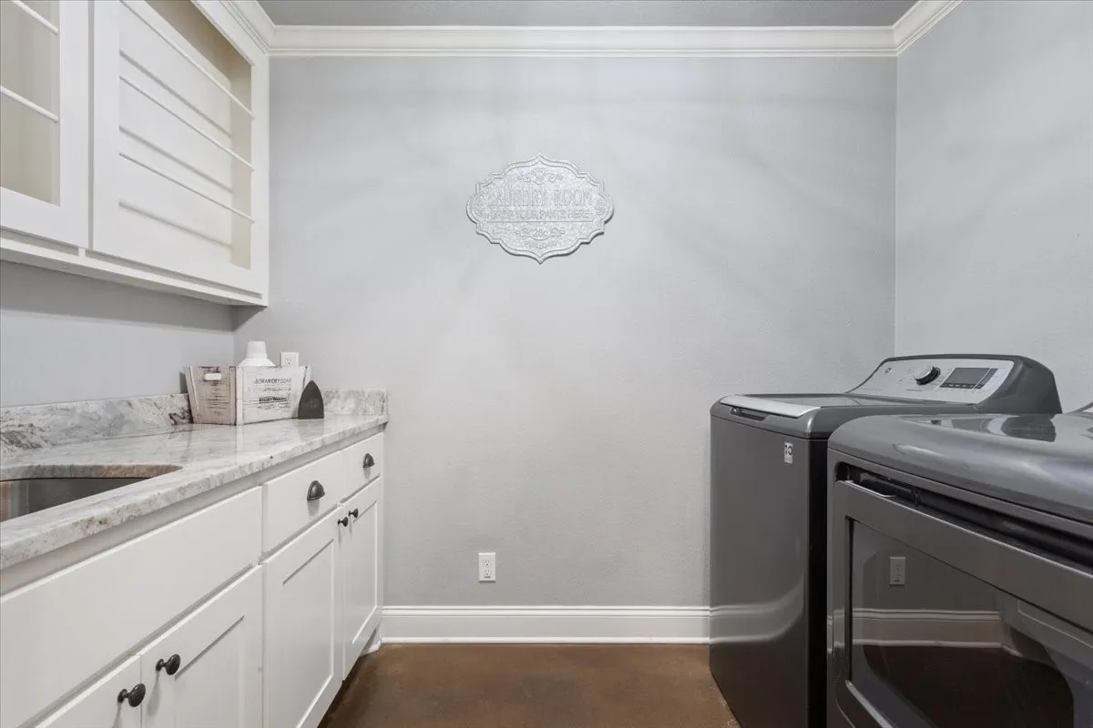 Laundry area with crown molding, washing machine and clothes dryer, and cabinet space
