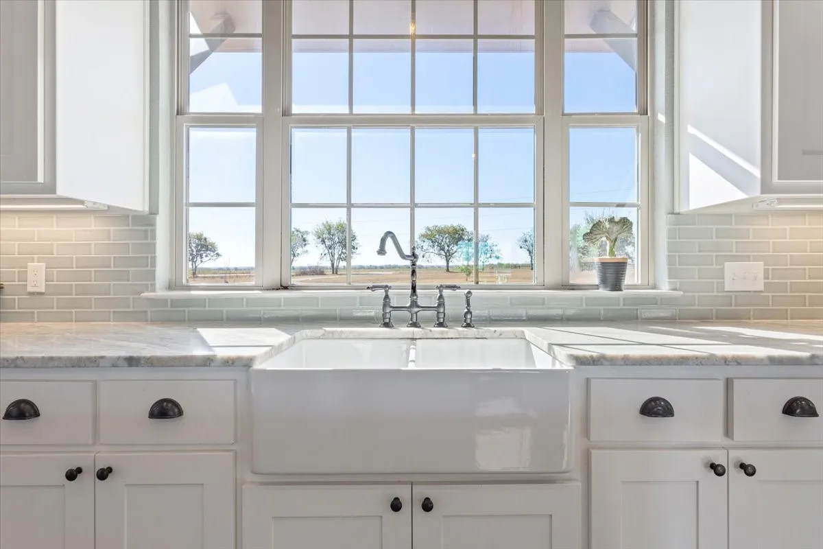 Kitchen with white cabinetry, tasteful backsplash, and light stone countertops