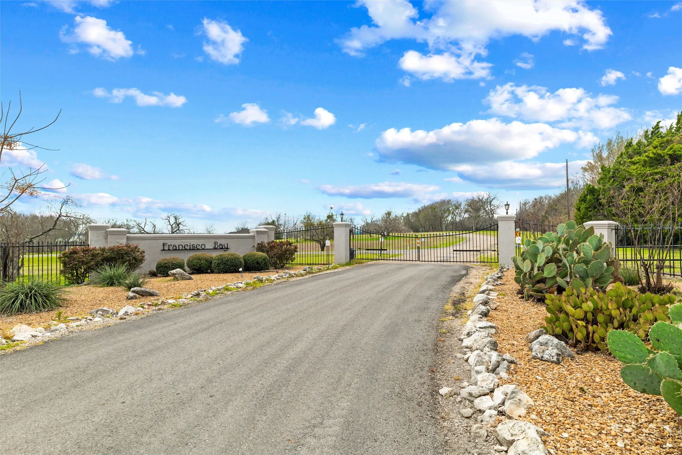 View of asphalt road featuring a gate and a gated entry