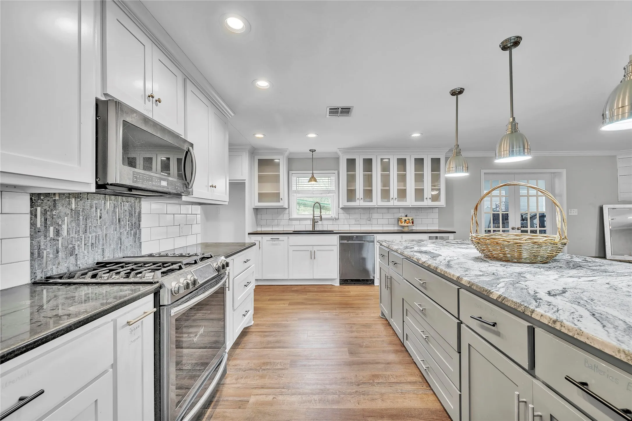 Kitchen featuring stainless steel appliances, glass insert cabinets, dark stone counters, tasteful backsplash, and dual tone cabinetry