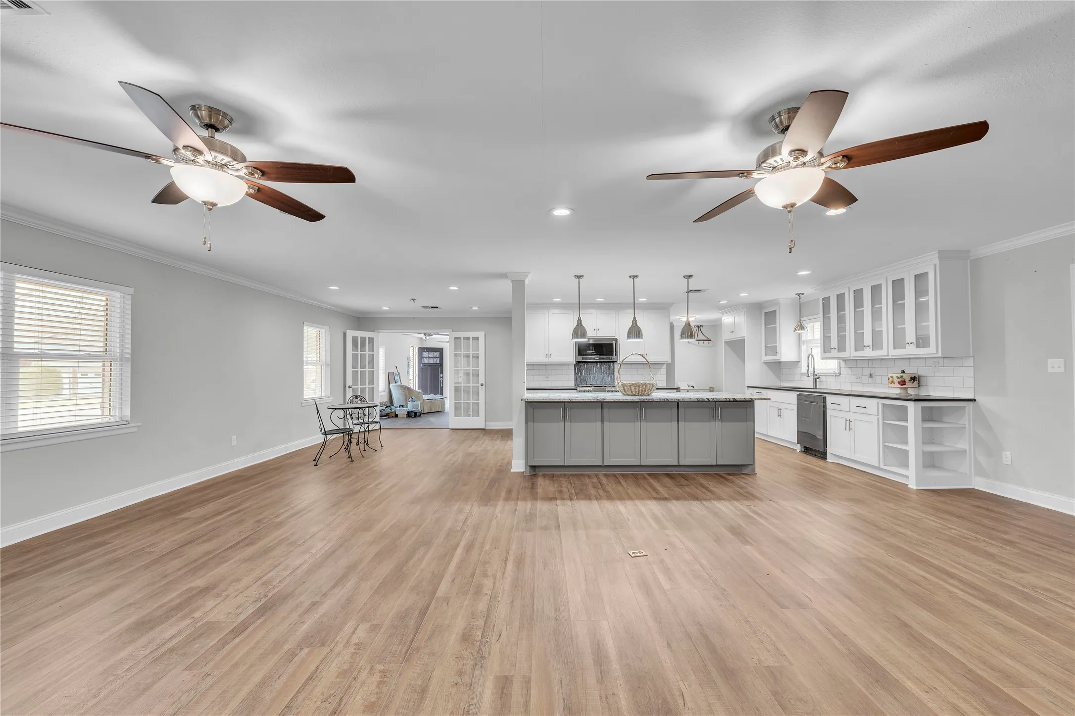 Kitchen with a ceiling fan, open floor plan, decorative backsplash, an island with sink, and crown molding