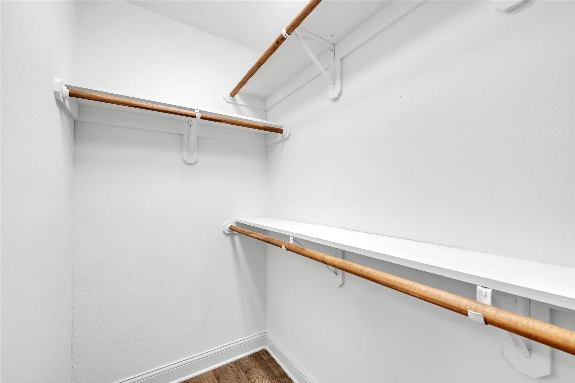 Walk in closet with dark wood-type flooring