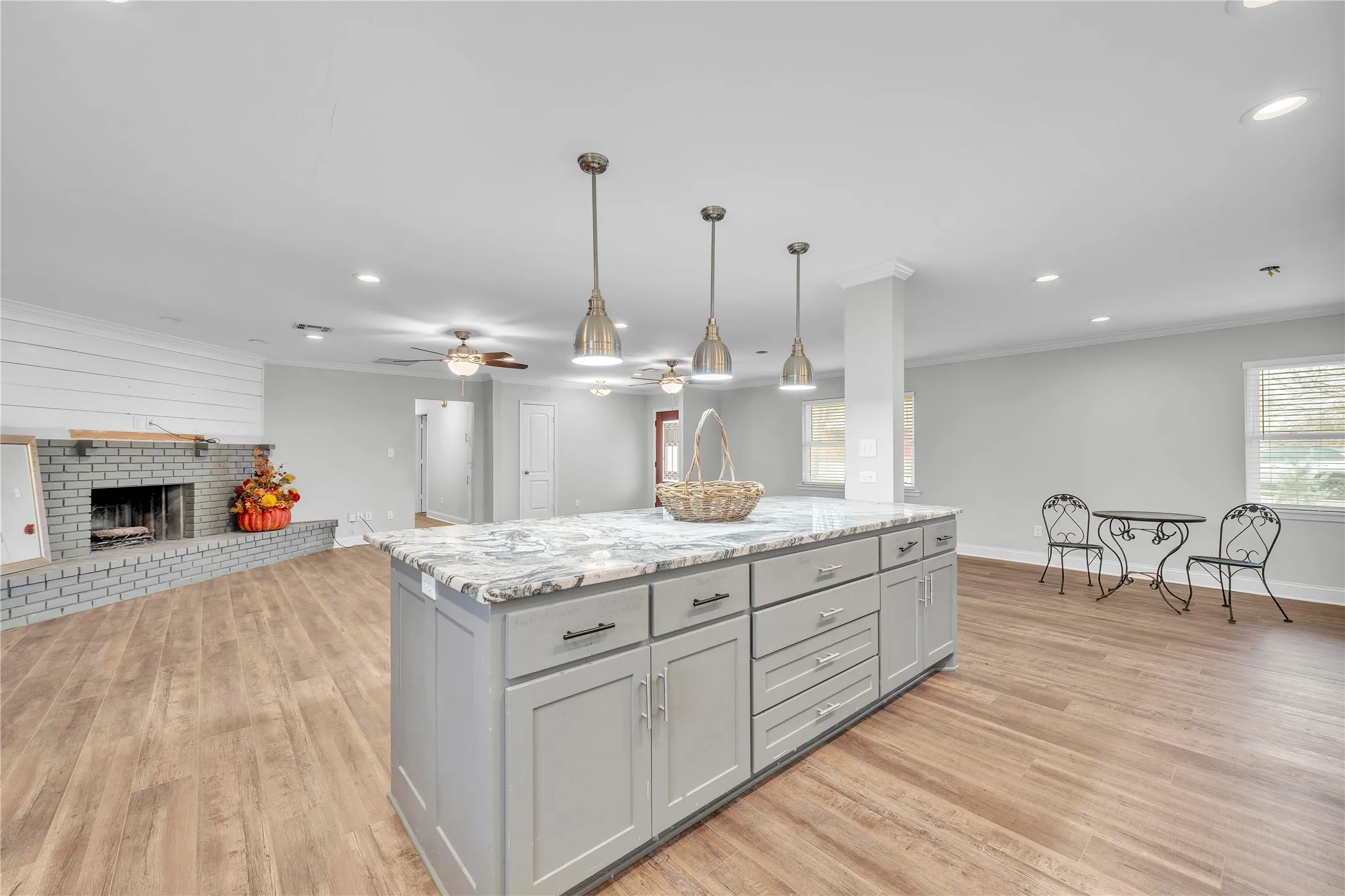 Kitchen featuring gray cabinetry, pendant lighting, open floor plan, a brick fireplace, and a kitchen island