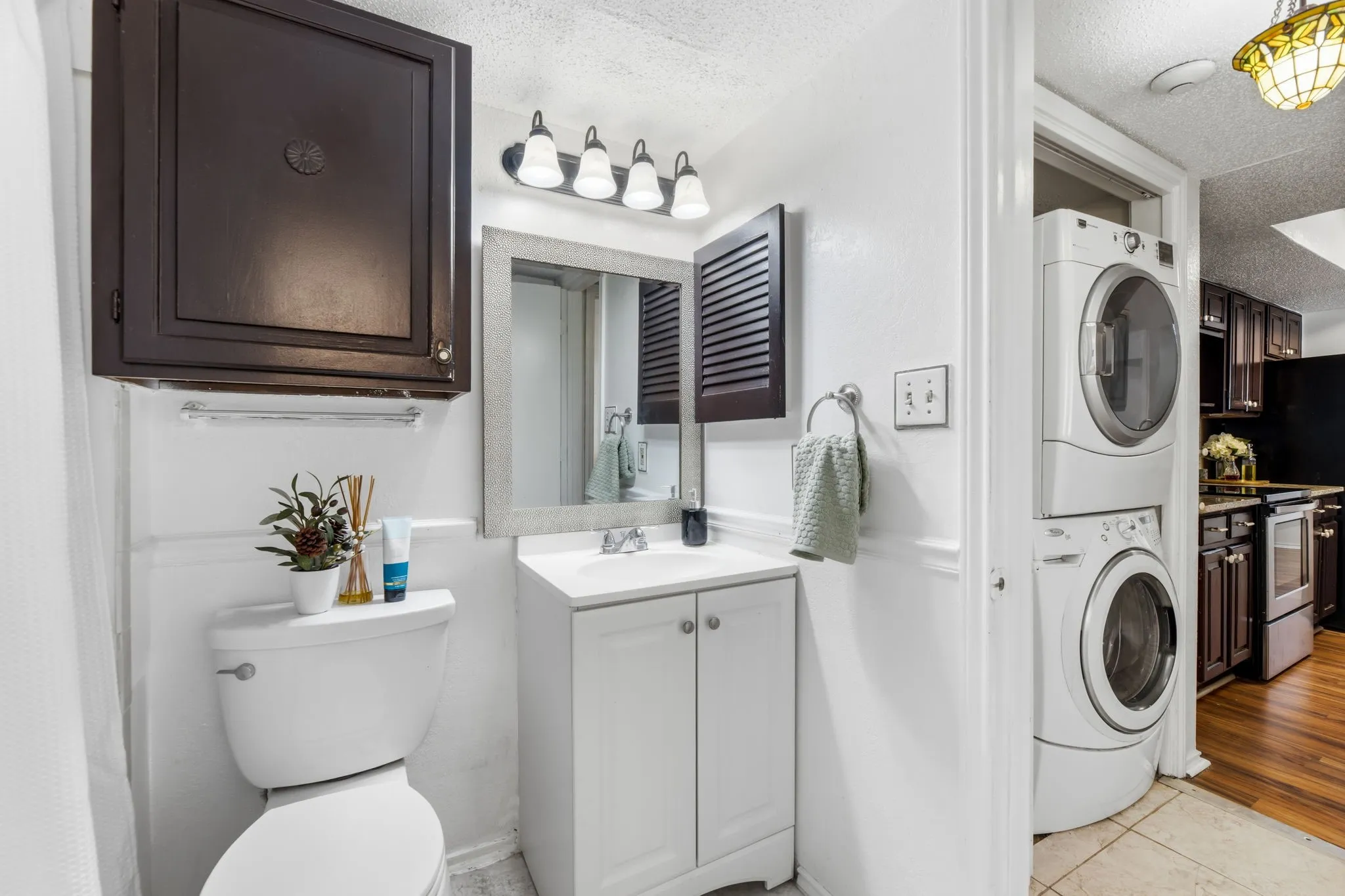 Bathroom with vanity, a textured ceiling, stacked washer and dryer, and light tile patterned floors