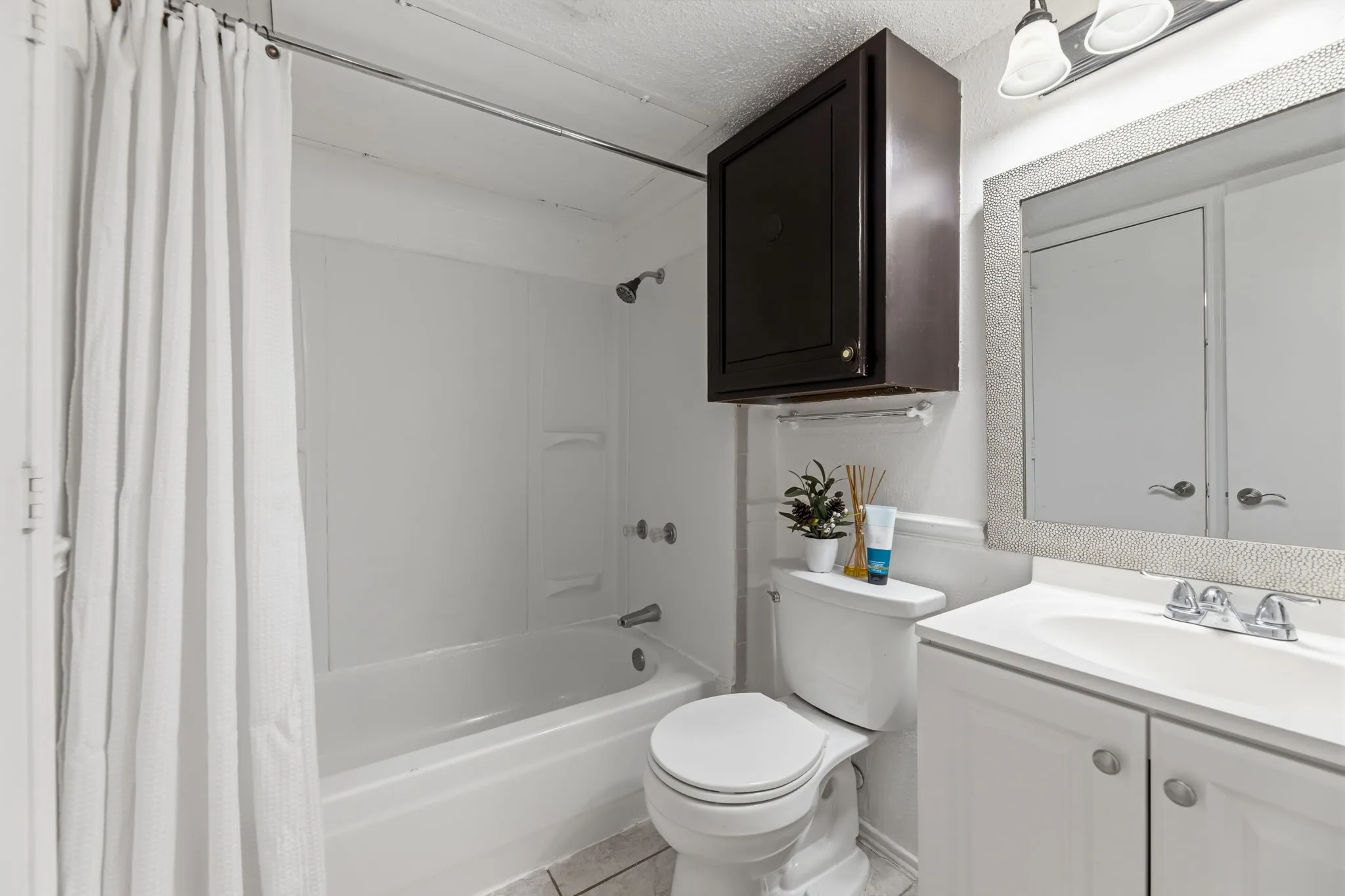Full bath featuring vanity, shower / bath combination with curtain, a textured ceiling, and light tile patterned flooring