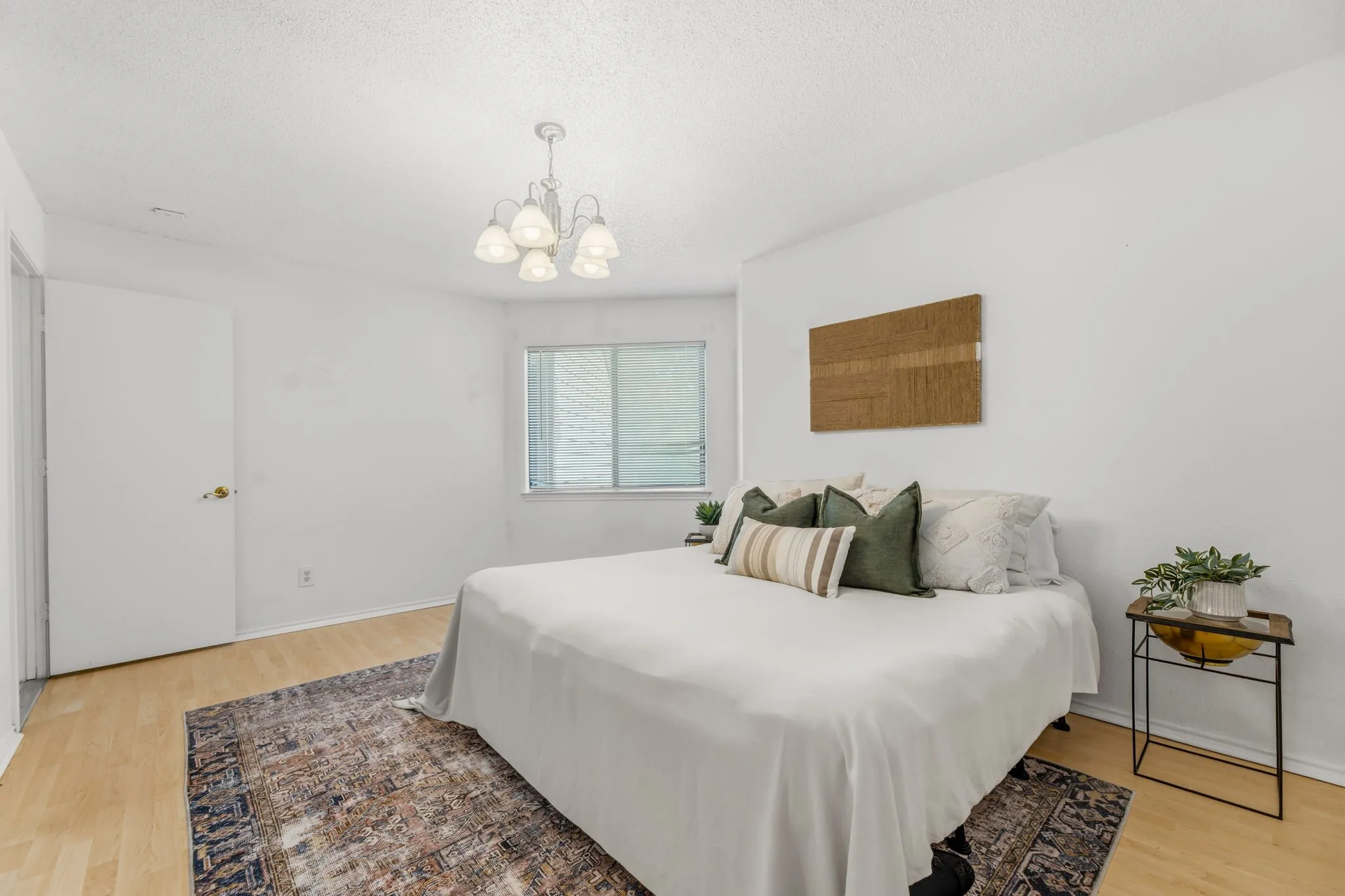 Bedroom featuring light wood-style floors, a chandelier, and a textured ceiling