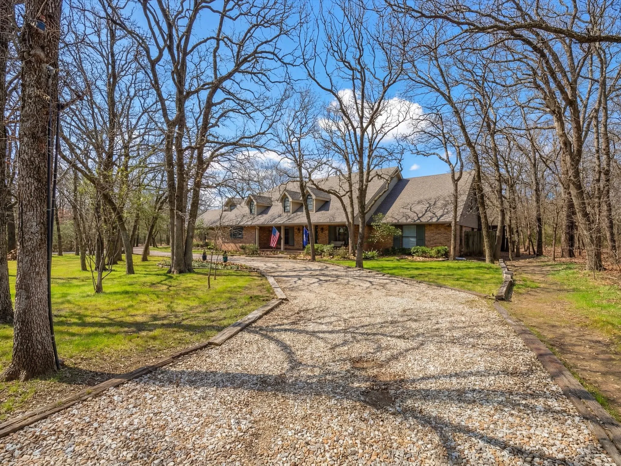 Cape cod home featuring brick siding, a front yard, and gravel driveway