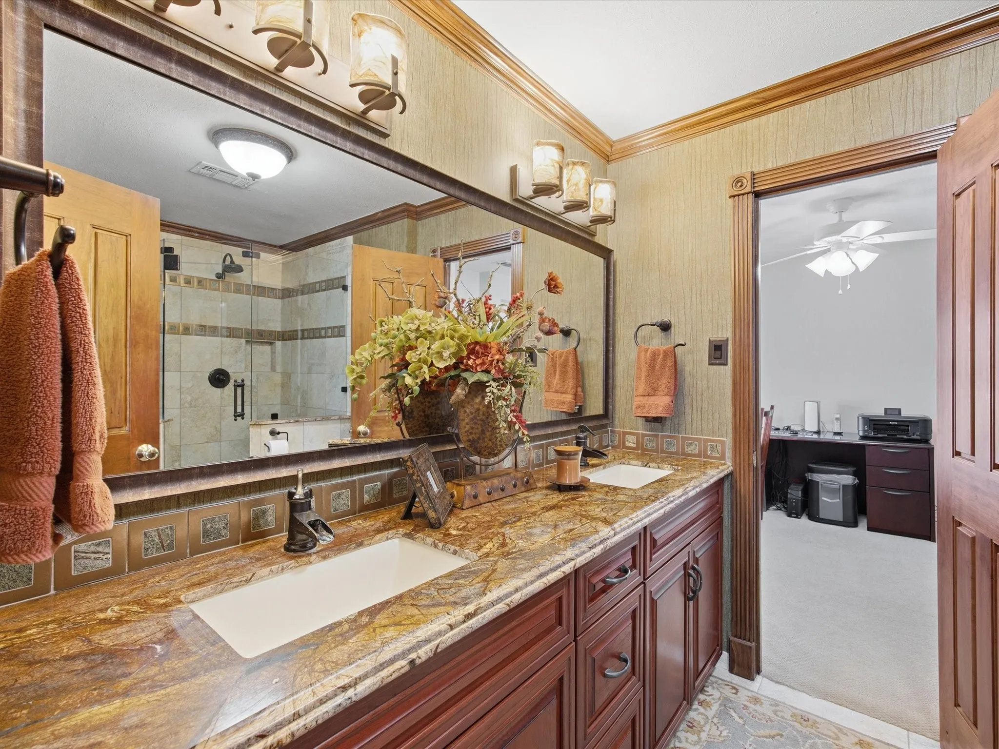 Full bathroom featuring a shower stall, ornamental molding, double vanity, ceiling fan, and light carpet