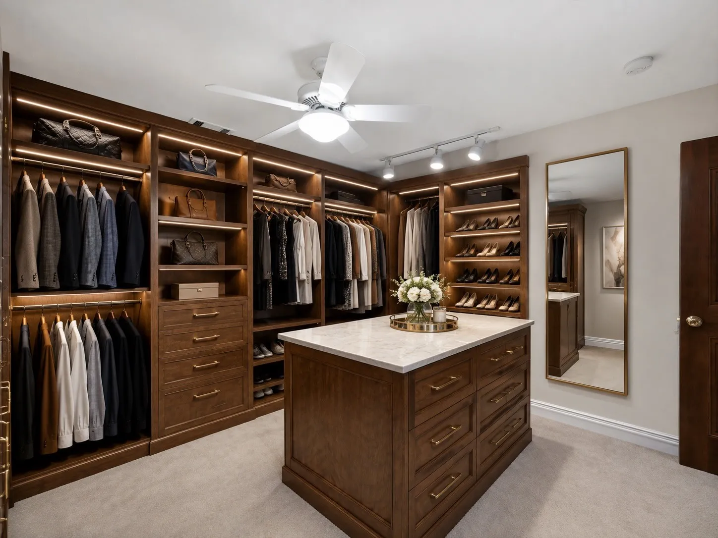 Virtually staged, custom wood-finish cabinetry featuring ample hanging and shelving space, integrated lighting, and a central dresser island style.